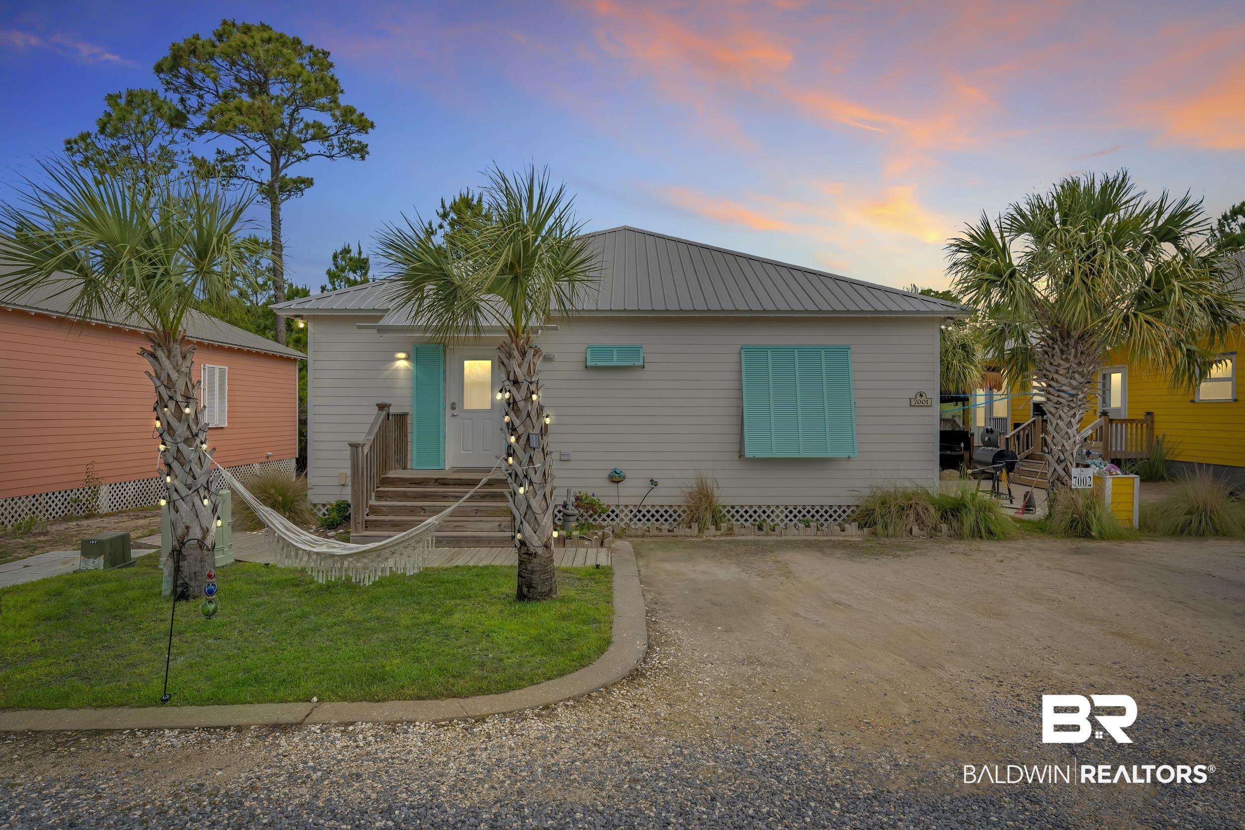 Image 2: Coastal-style home featuring horizontal siding, a metal roof, and a turquoise front door