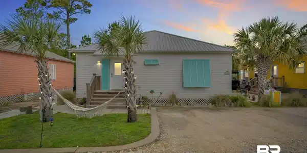 Image 2: Coastal-style home featuring horizontal siding, a metal roof, and a turquoise front door