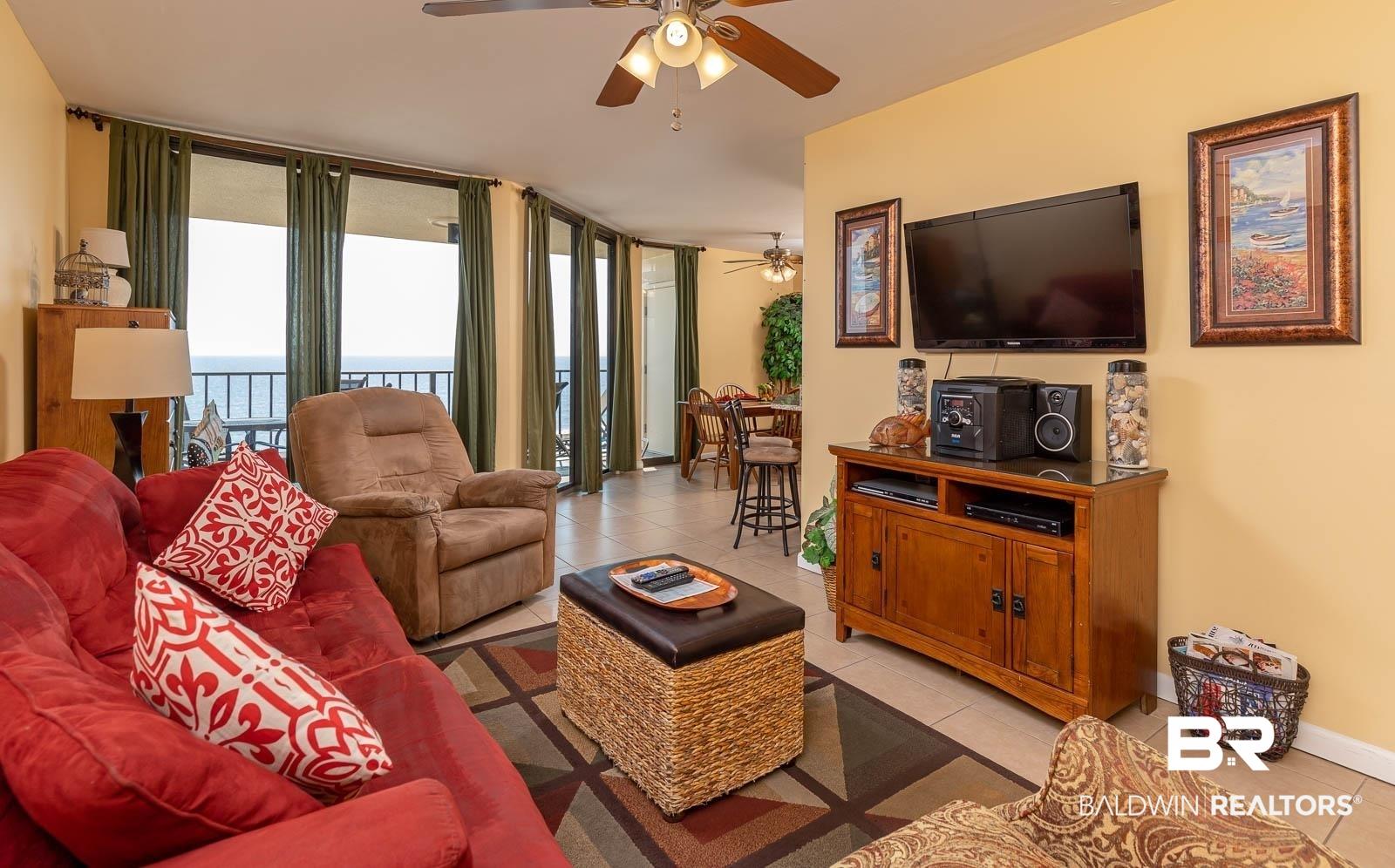 Image 2: Living area featuring tile flooring, a ceiling fan, and multiple floor-to-ceiling glass doors