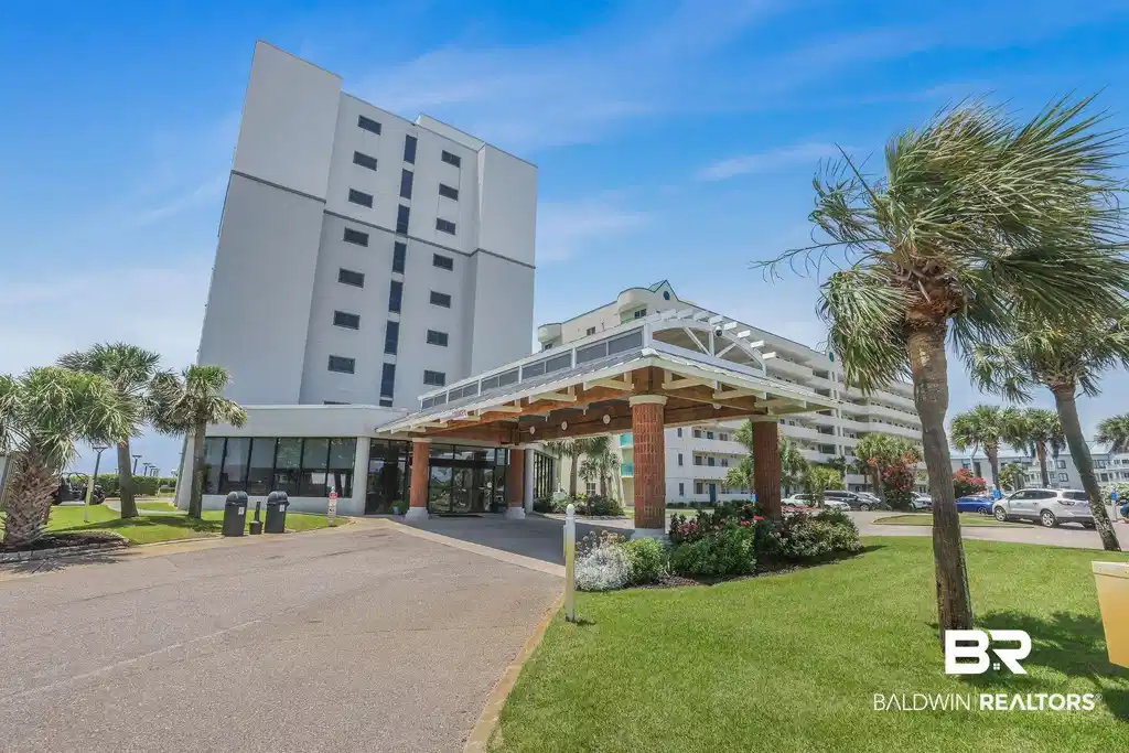 Image 1: Modern high-rise building featuring a covered portico entrance with architectural detailing, lush landscaping, and mature palm trees