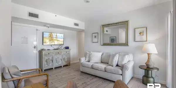 Image 4: Living area featuring wood-finish flooring, a decorative console, and neutral wall tones