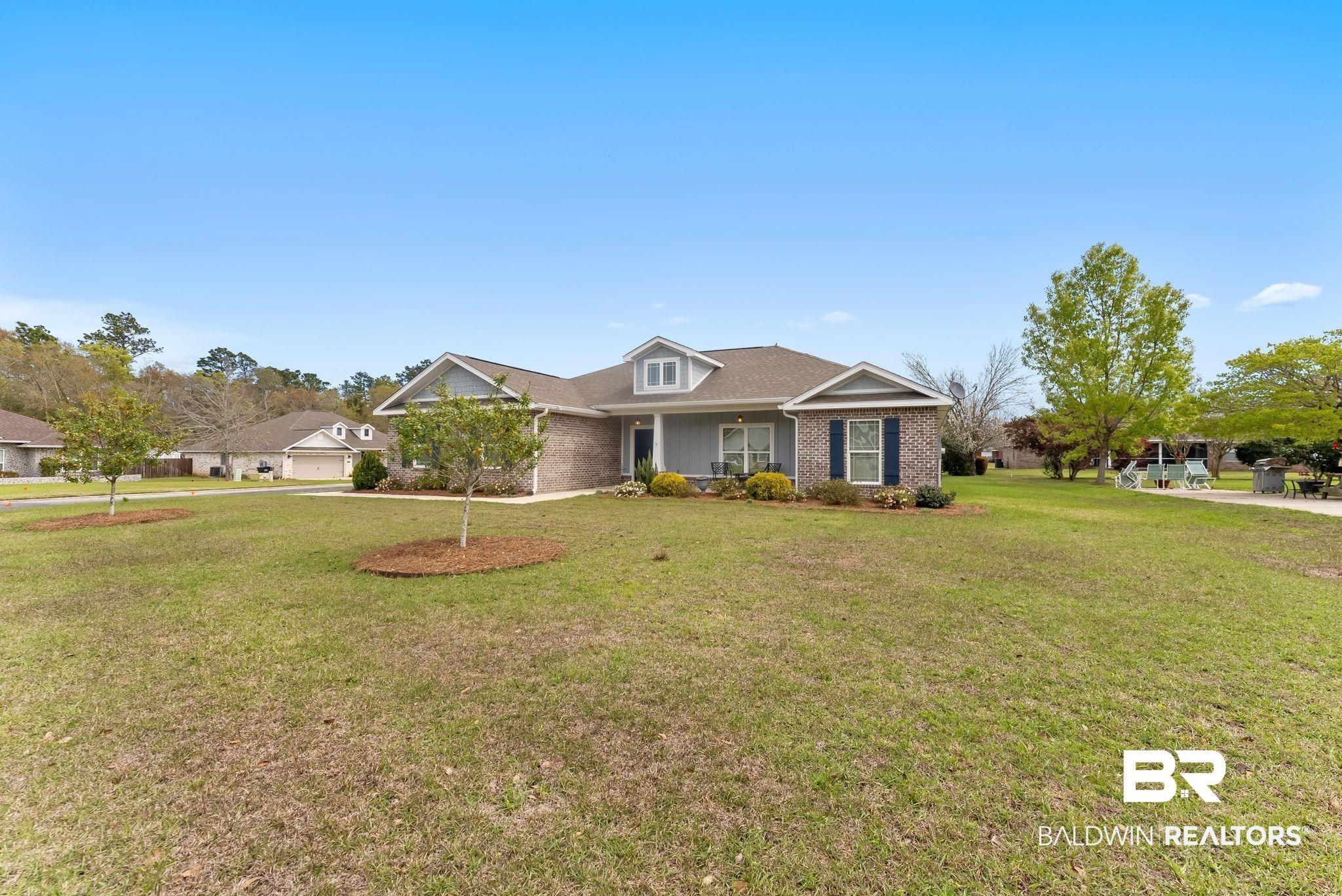 Image 3: View of front of home with brick siding, covered porch, and a front lawn
