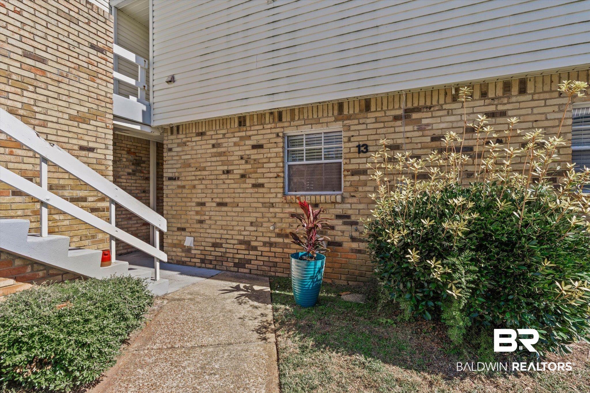 Image 2: Brick exterior featuring horizontal vinyl siding and concrete stairs with white railings
