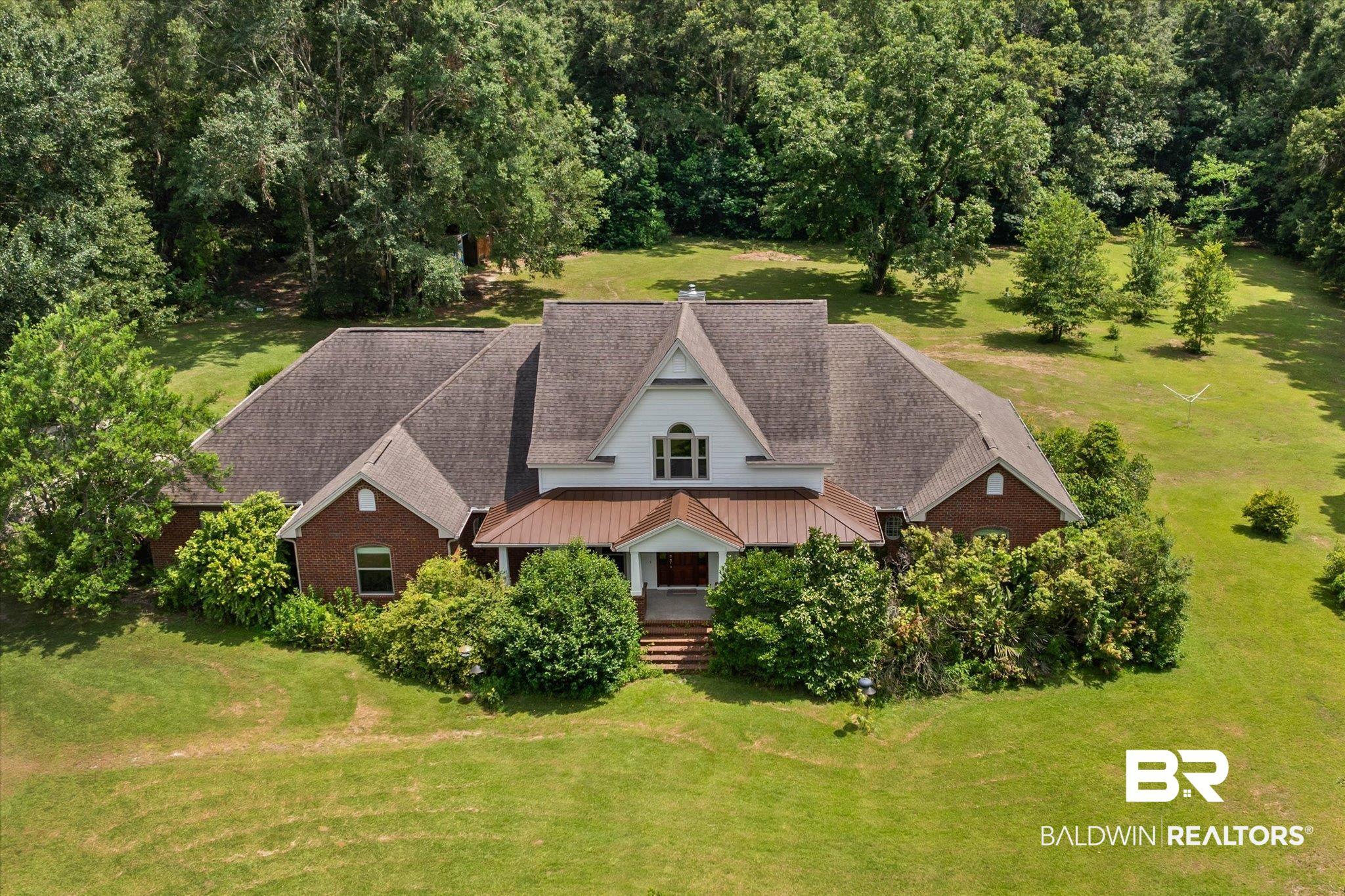 Image 1: Expansive brick and white-sided residence featuring a prominent gabled roofline and a front porch with a copper-toned metal roof