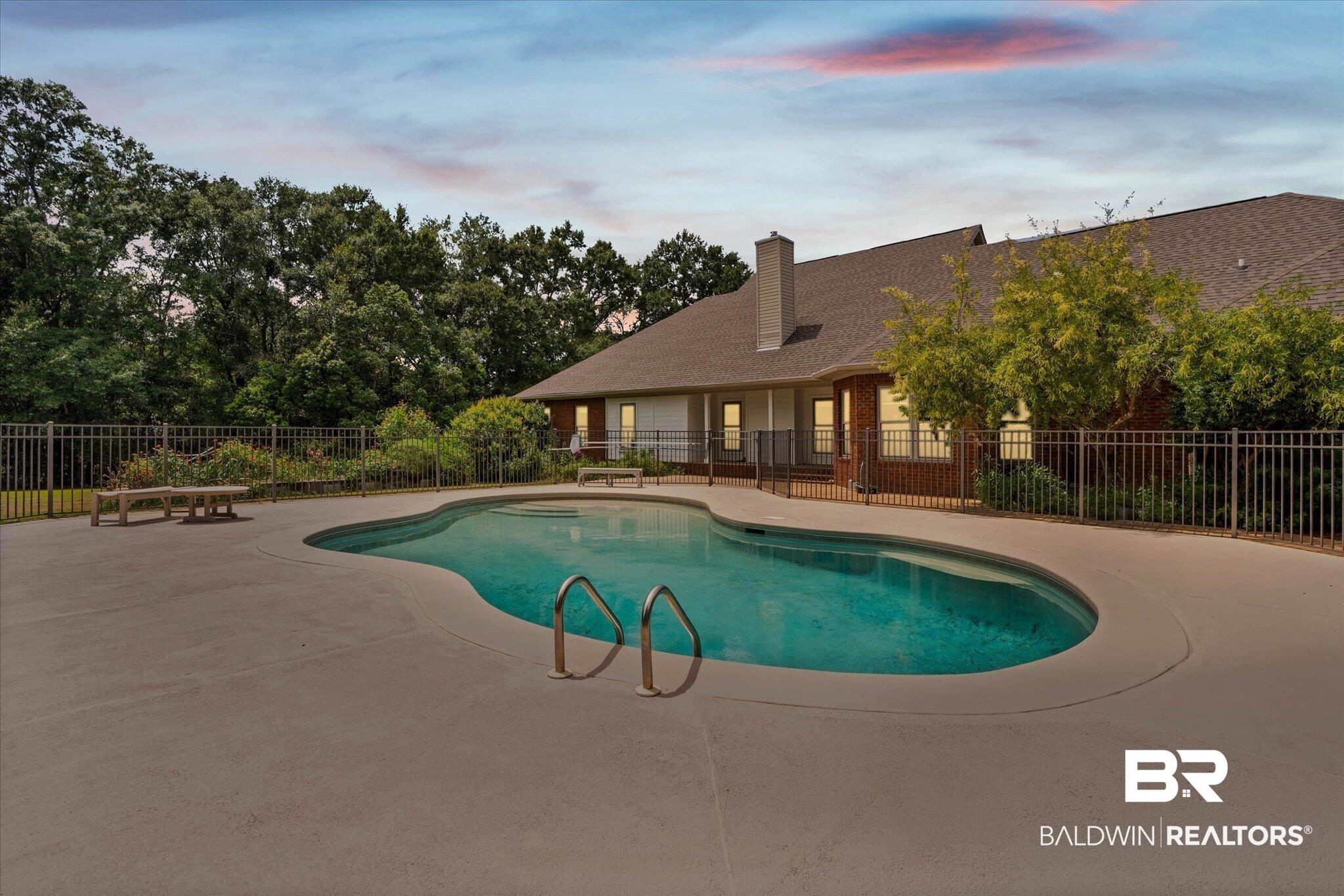 Image 2: Freeform swimming pool with integrated steps, surrounded by a concrete patio