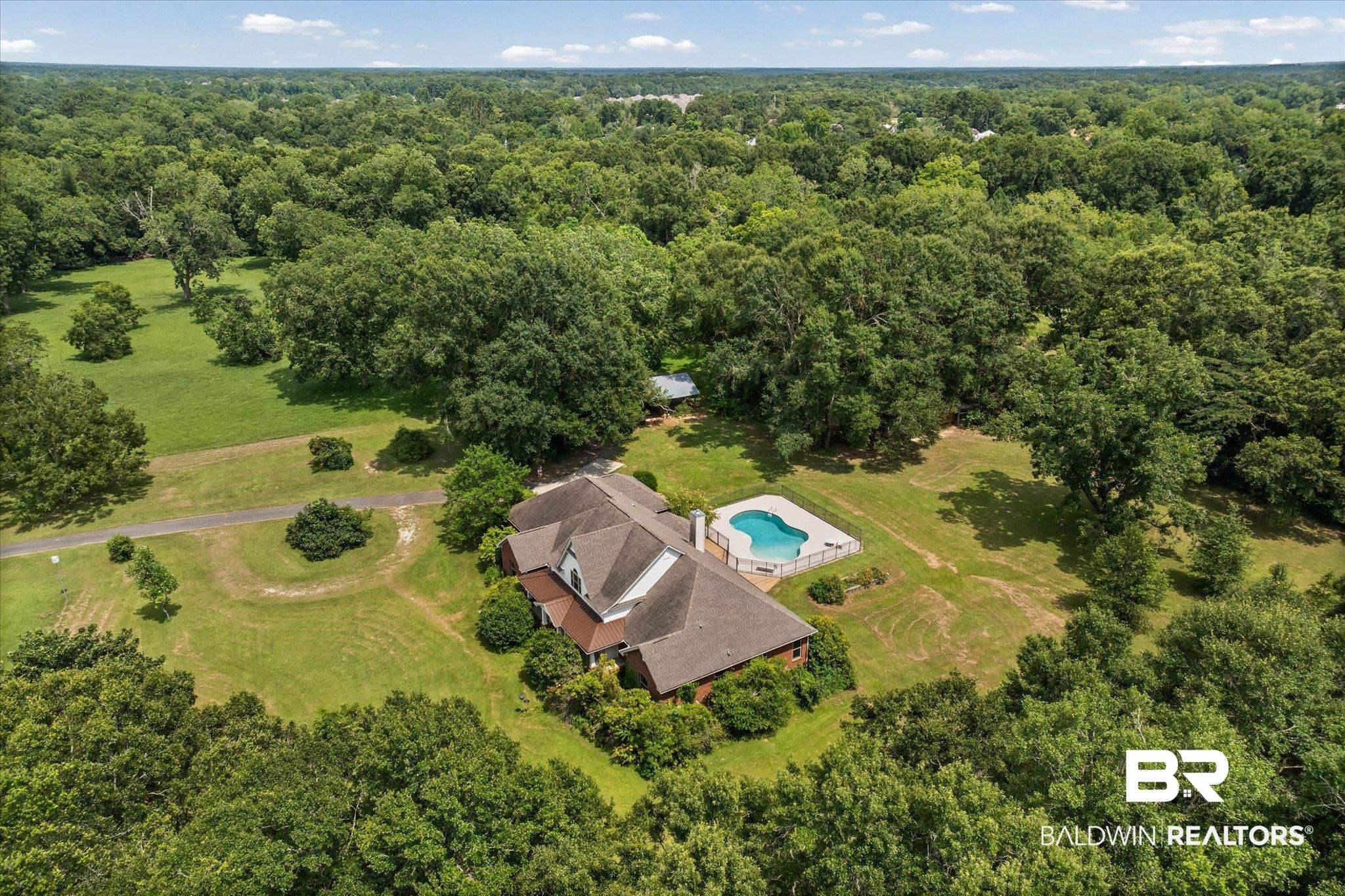 Image 3: Sprawling property featuring a multi-gabled residence, an in-ground swimming pool, and extensive green space with mature trees