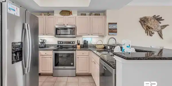 Image 2: Kitchen with stainless steel appliances, crown molding, dark stone counters, light wood finish cabinets, and light tile patterned flooring