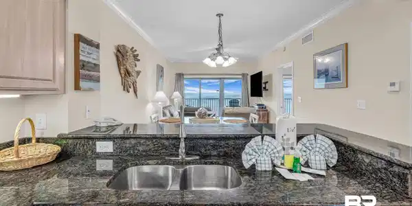 Image 3: Kitchen with light wood finish cabinets, open floor plan, dark stone countertops, suspended lighting, and ornamental molding