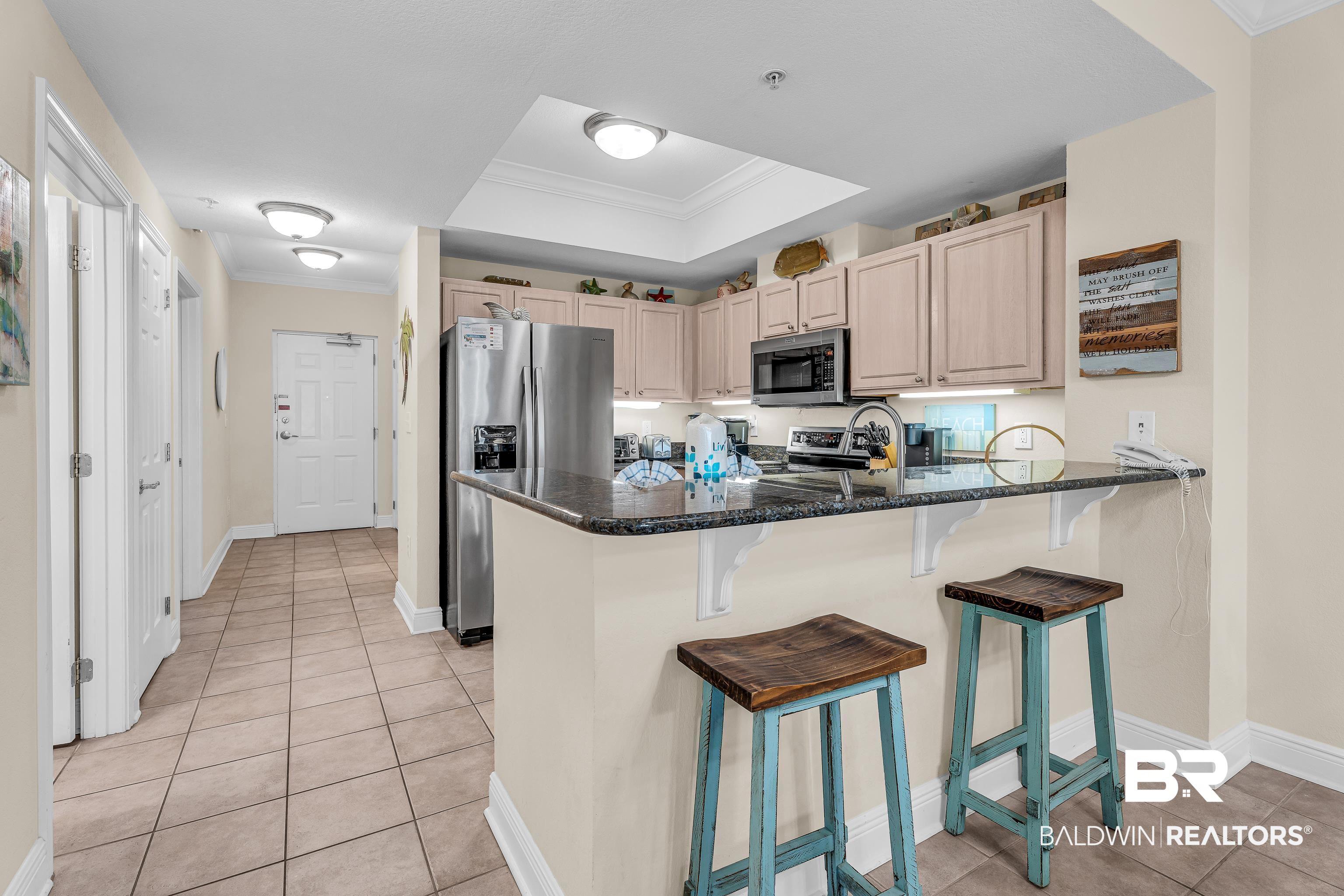 Image 4: Kitchen featuring a kitchen breakfast bar, crown molding, stainless steel appliances, a peninsula, and light tile patterned flooring