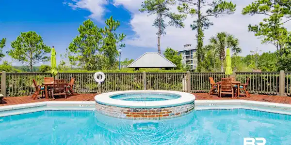 Image 2: Outdoor swimming pool with an integrated circular spa, surrounded by a wood-finish deck
