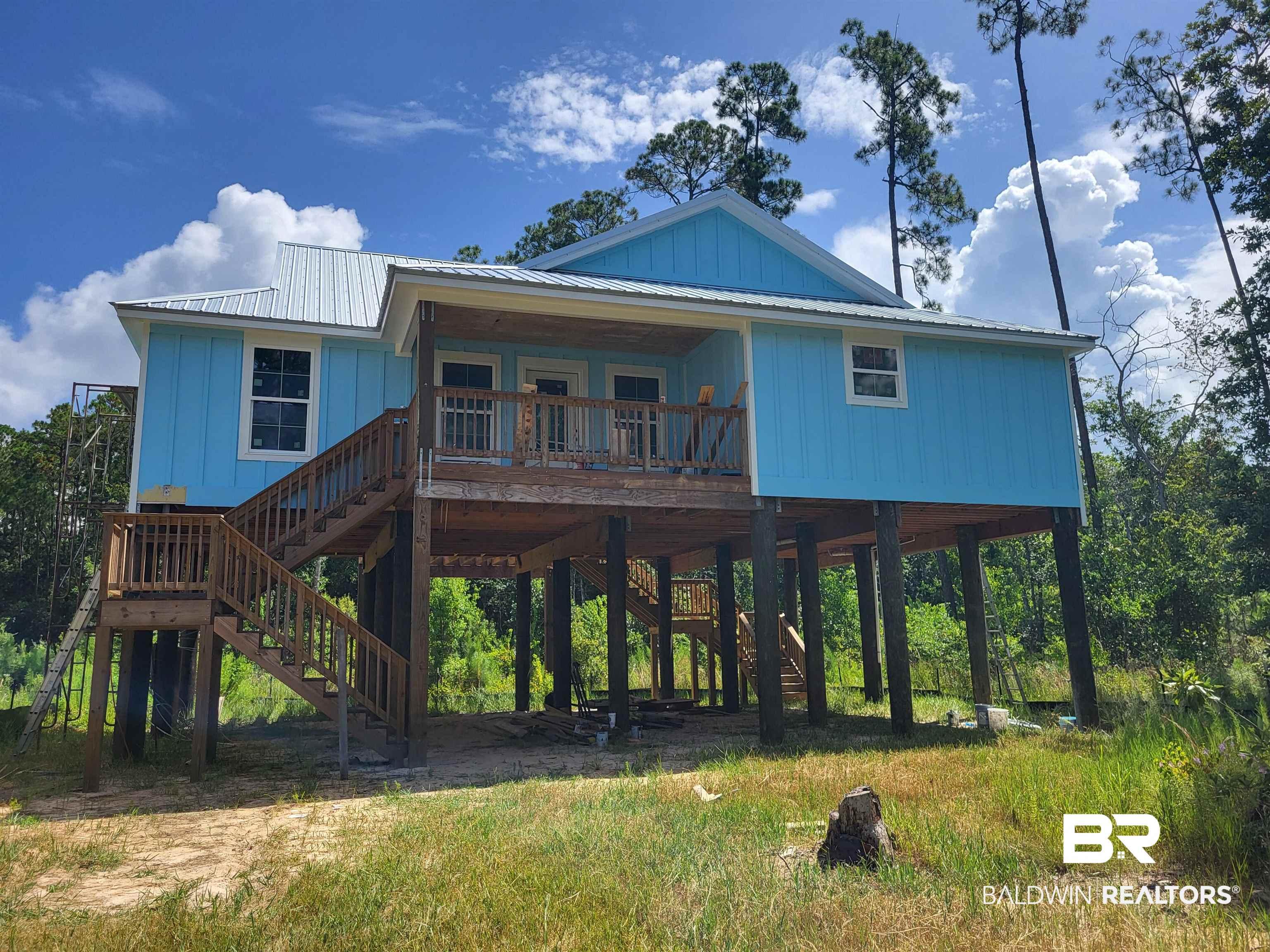 Image 2: Stilt foundation residence featuring blue vertical siding and a metal roof