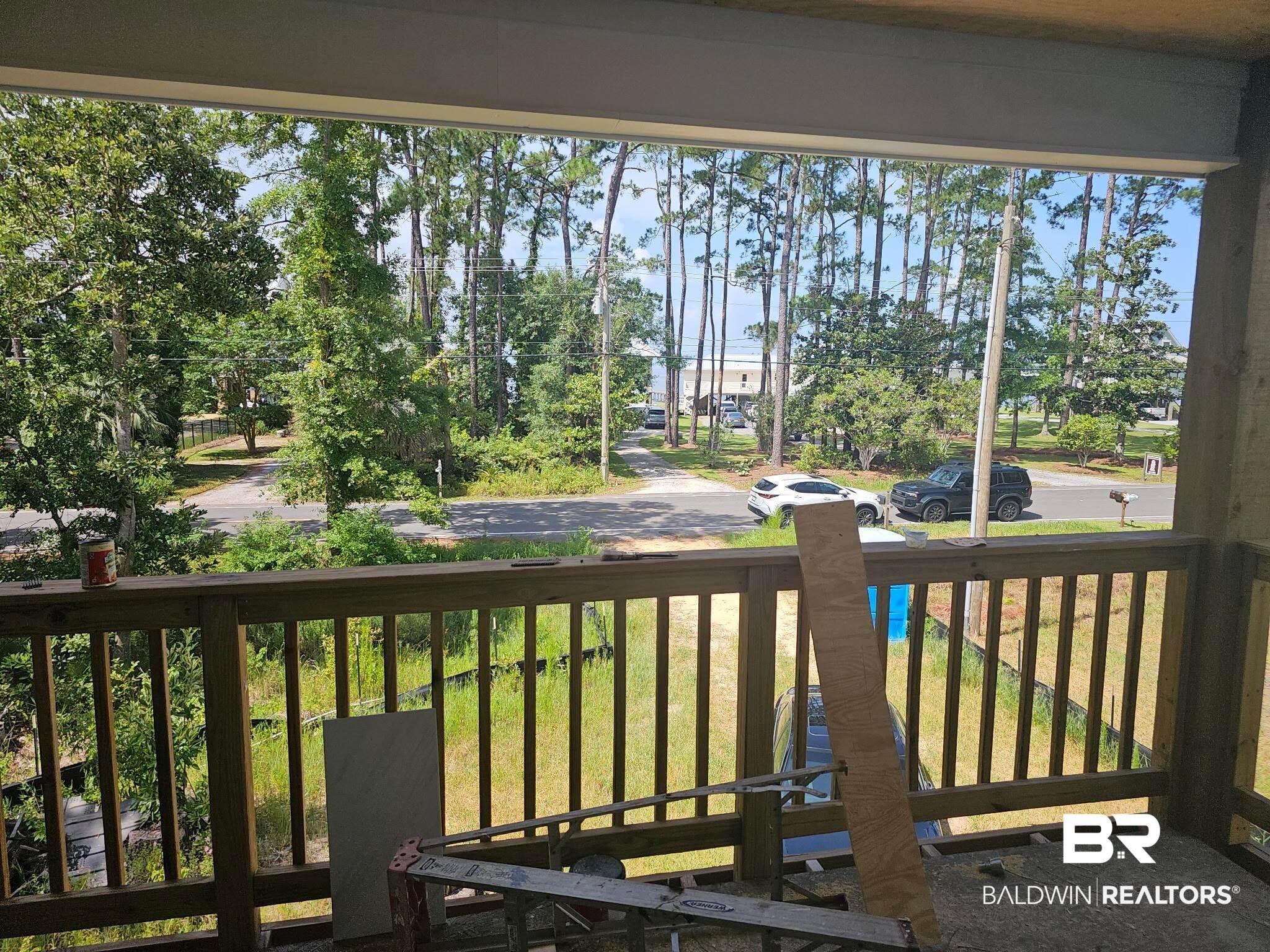 Image 3: Balcony featuring wood railings, offering tree-lined surroundings and distant water visibility