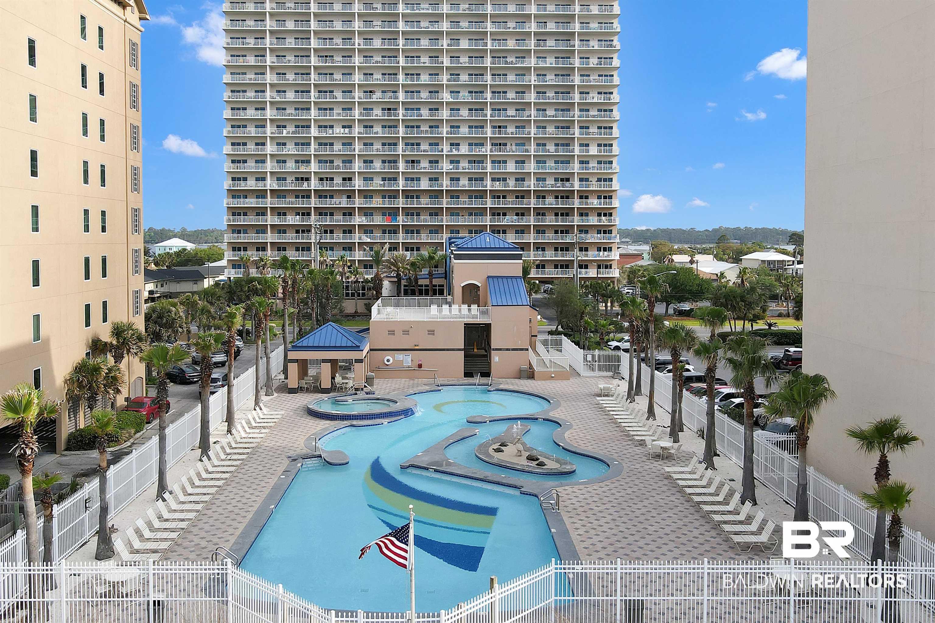 Image 2: Resort-style pool area featuring a large, irregularly shaped swimming pool with integrated water features, a separate hot tub, and an adjacent cabana structure