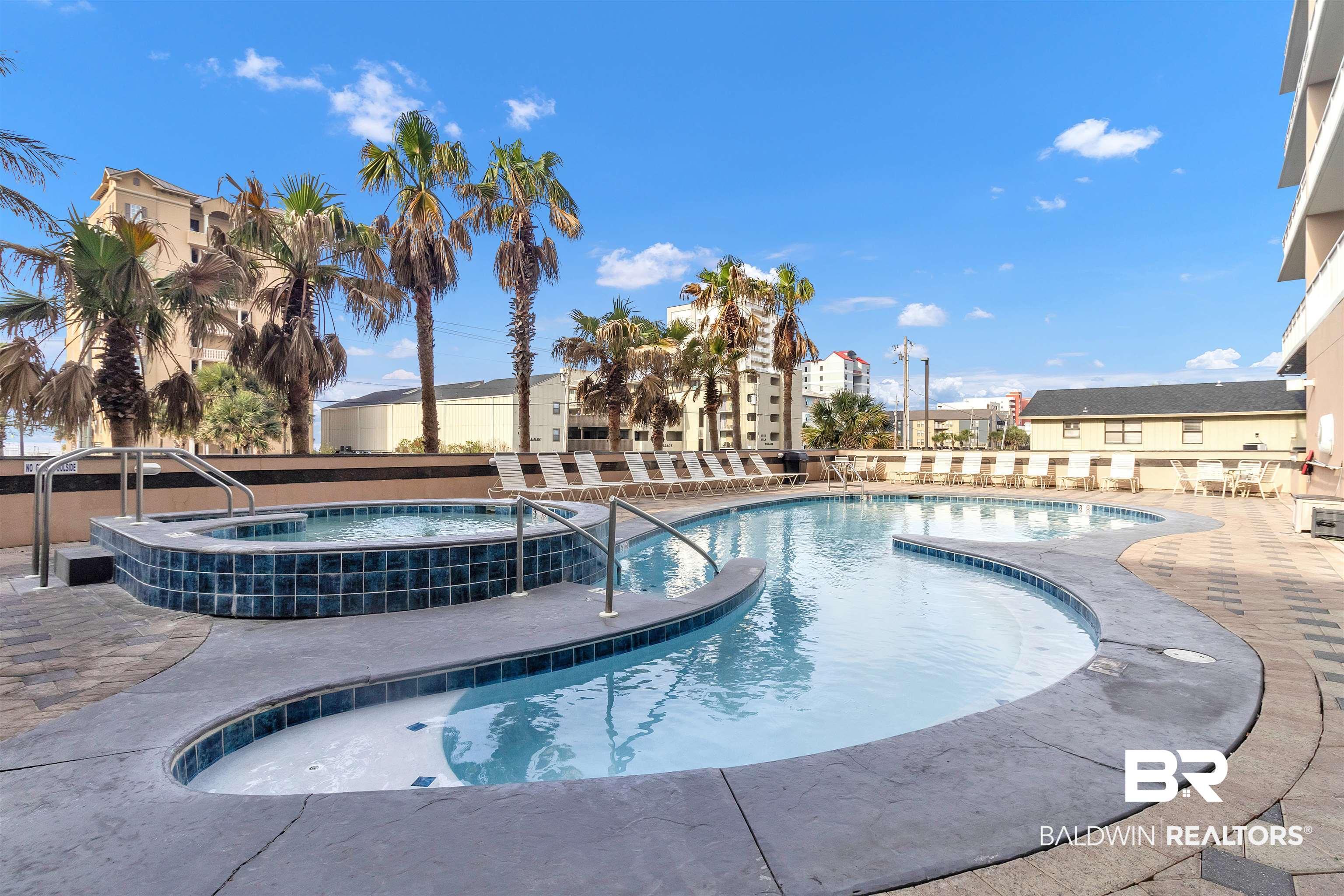 Image 3: Resort-style outdoor pool area featuring a freeform swimming pool, integrated spa, and expansive paver deck