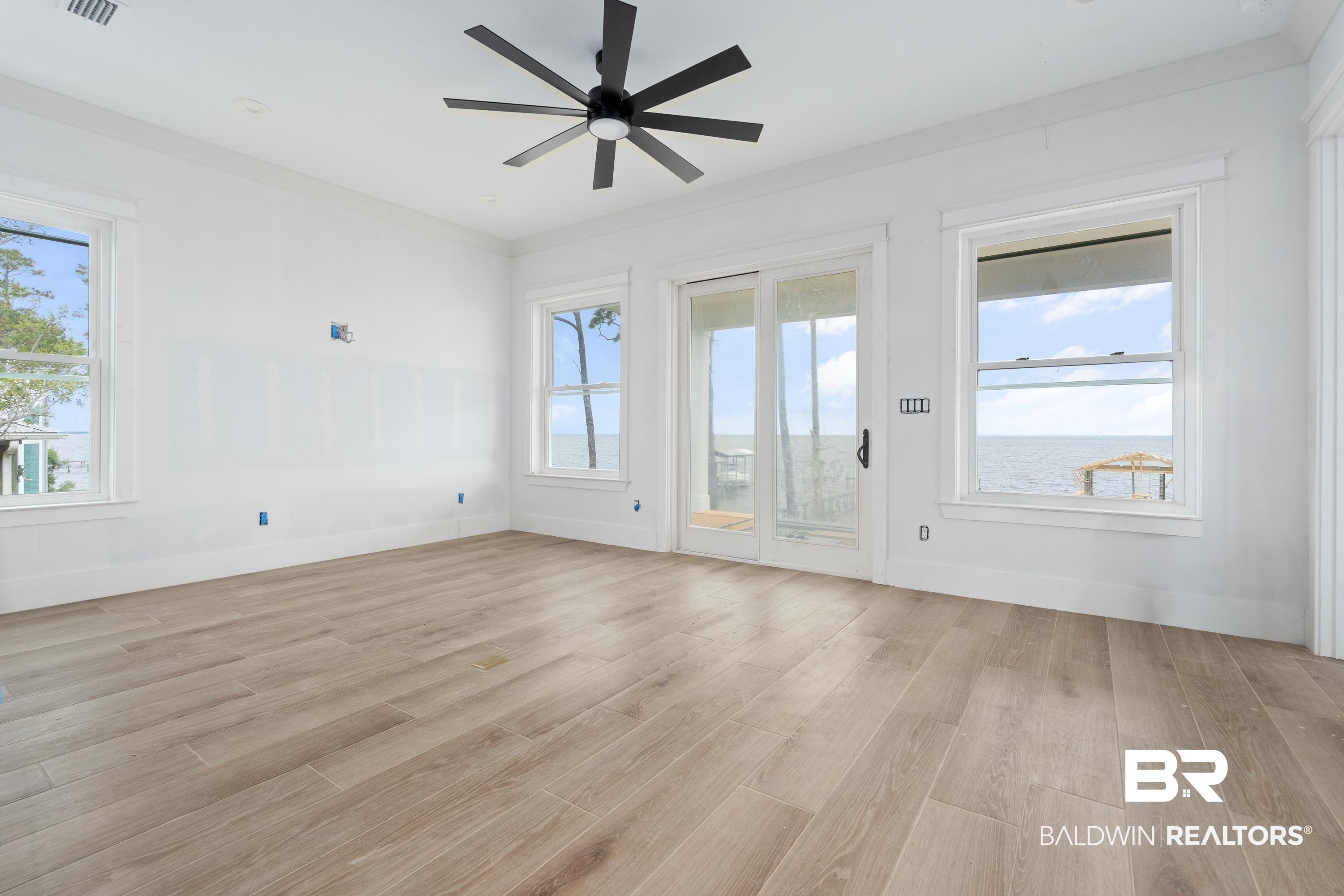 Image 2: Expansive room featuring light wood-finish flooring and a contemporary black ceiling fan