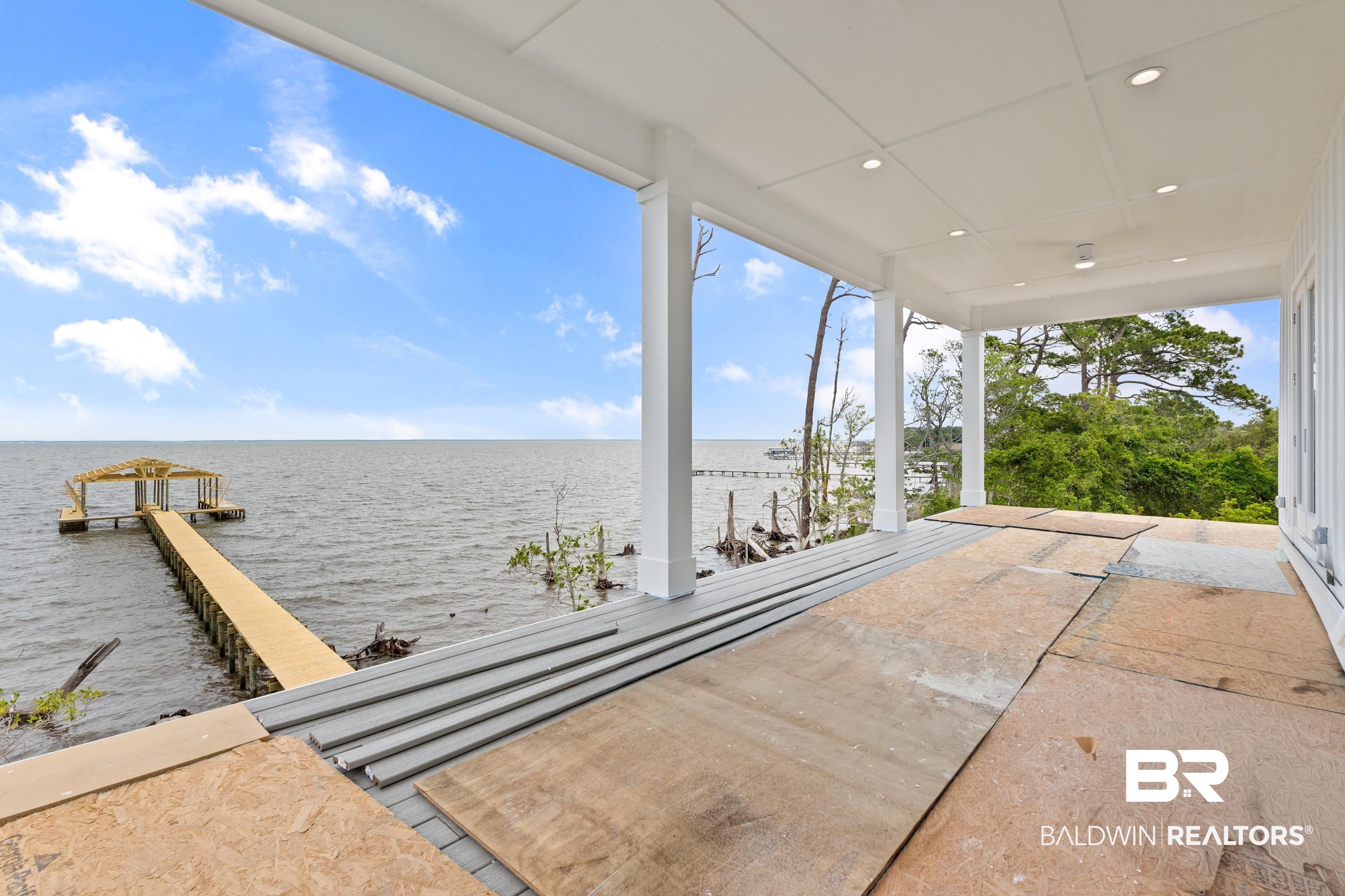 Image 3: Expansive covered porch featuring a waterside setting, a private pier with a covered boat dock, and surrounding mature trees