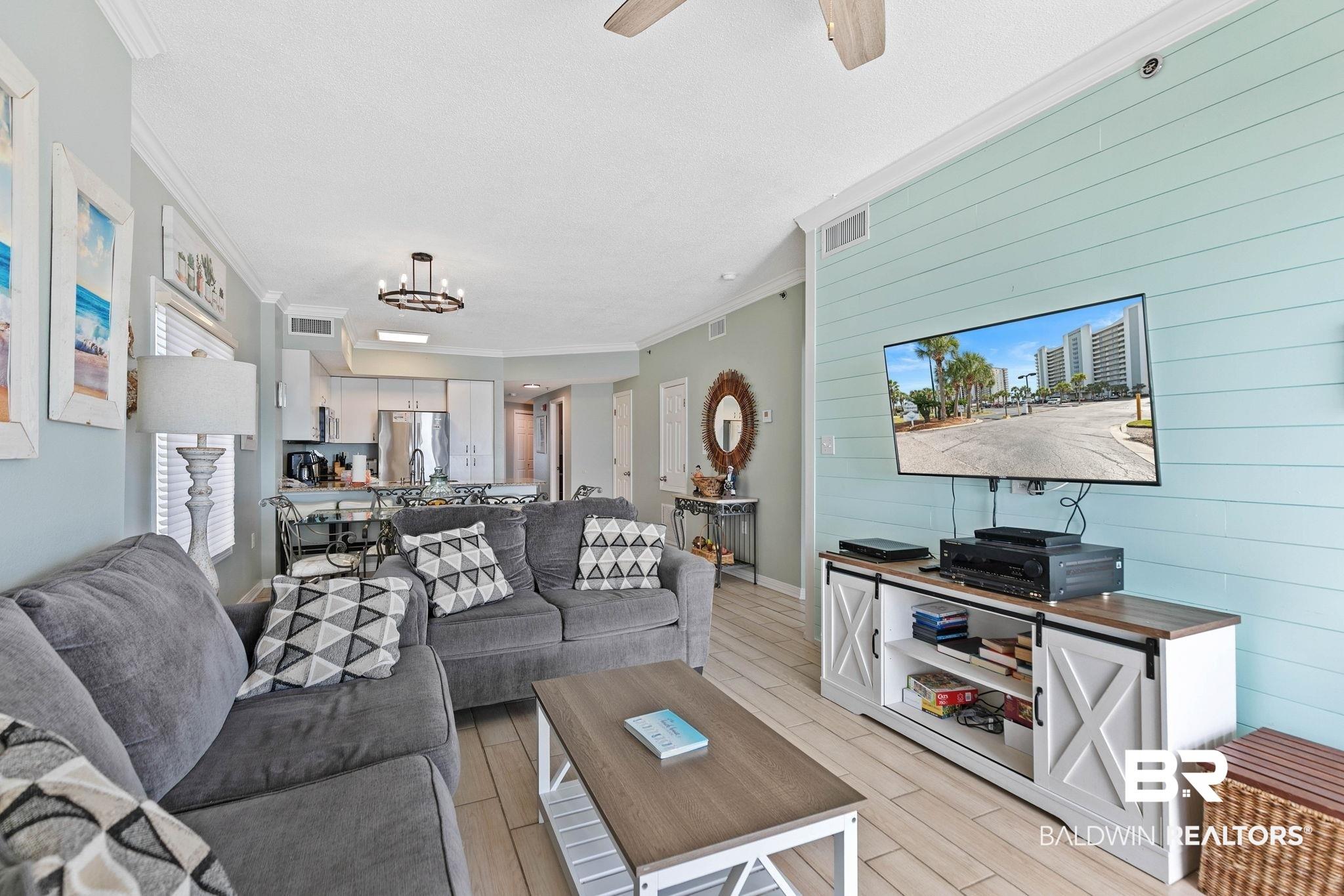 Image 3: Living room featuring wood tiled floors, wood walls, ceiling fan, and crown molding