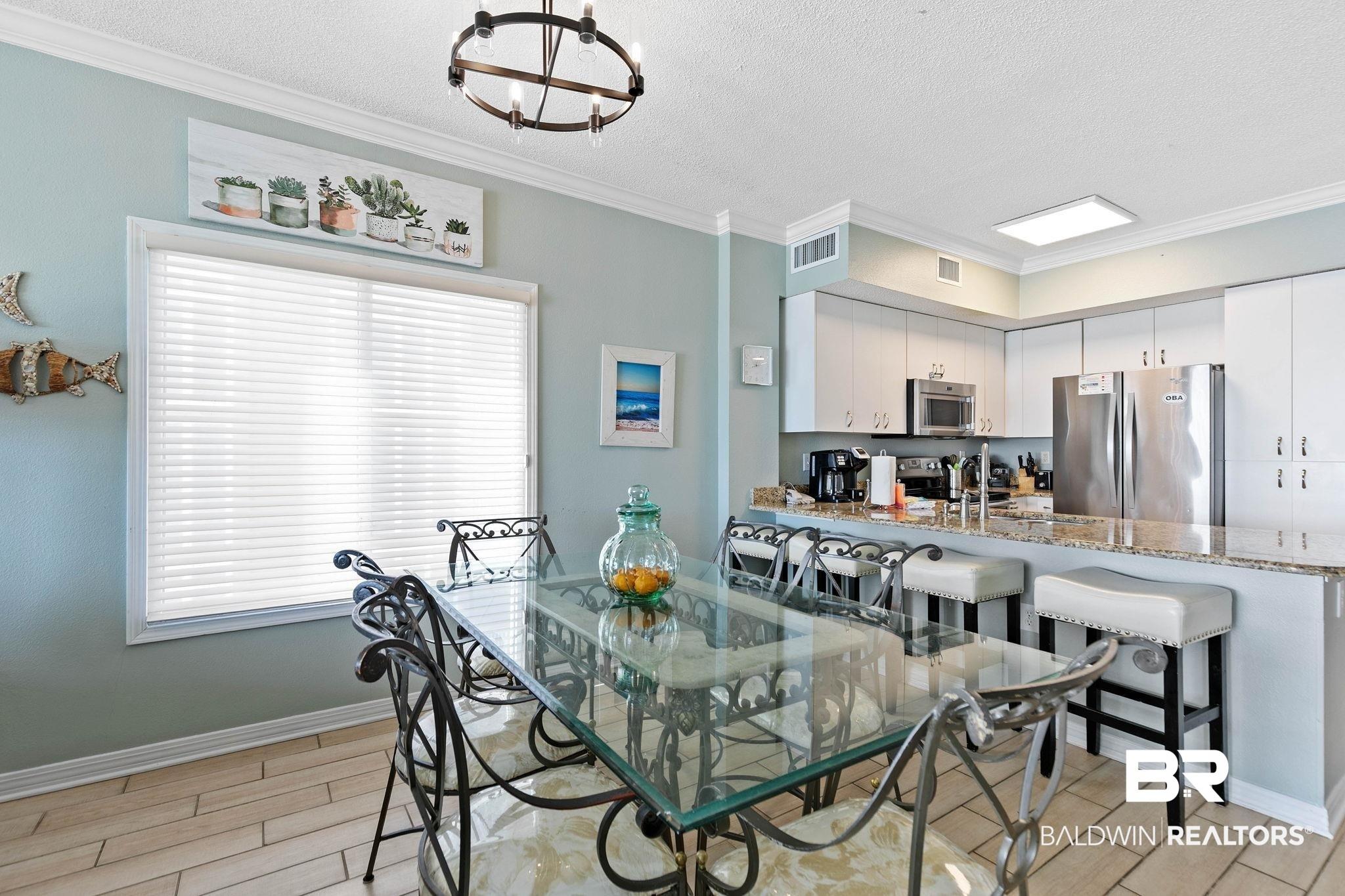 Image 4: Dining space with wood finish floors, crown molding, hanging lights, and a textured ceiling