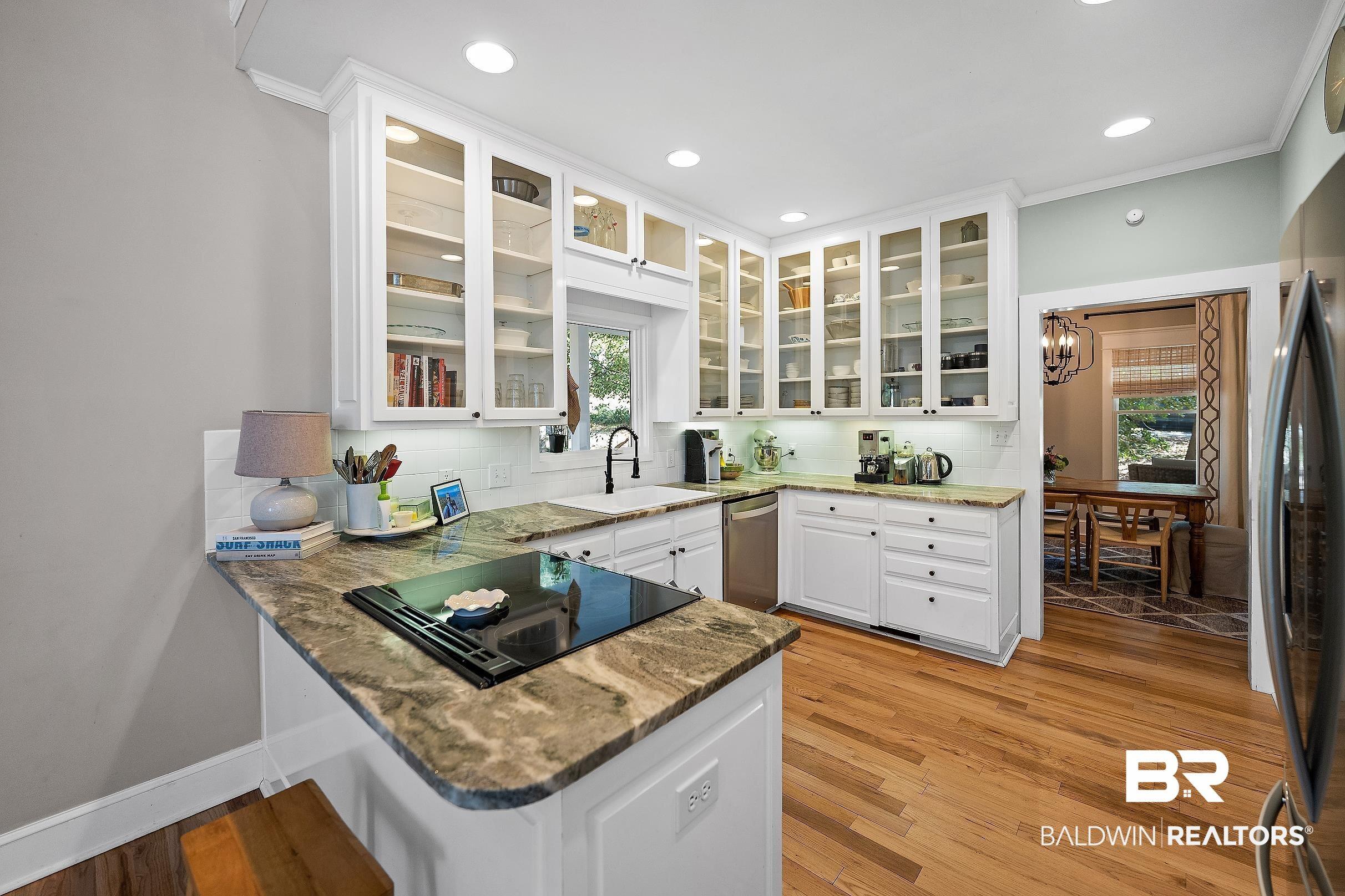 Image 4: Kitchen with glass fronted cabinets, a peninsula, backsplash, dark stone countertops, and ornamental molding