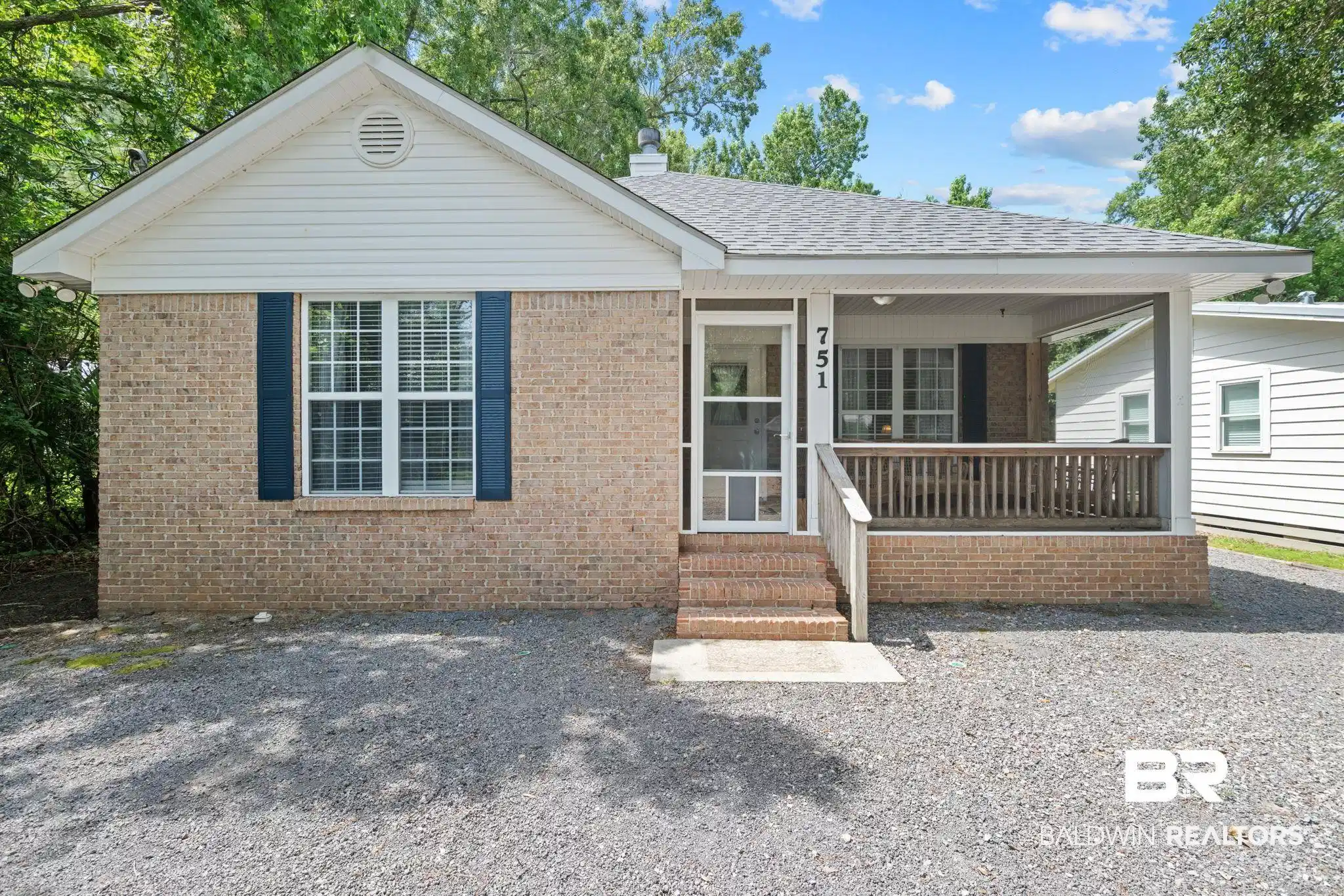 Image 1: Brick exterior with a covered porch, white siding, and dark blue shutters