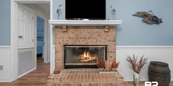 Image 3: Brick fireplace with a white mantel and hearth, complemented by a television placement