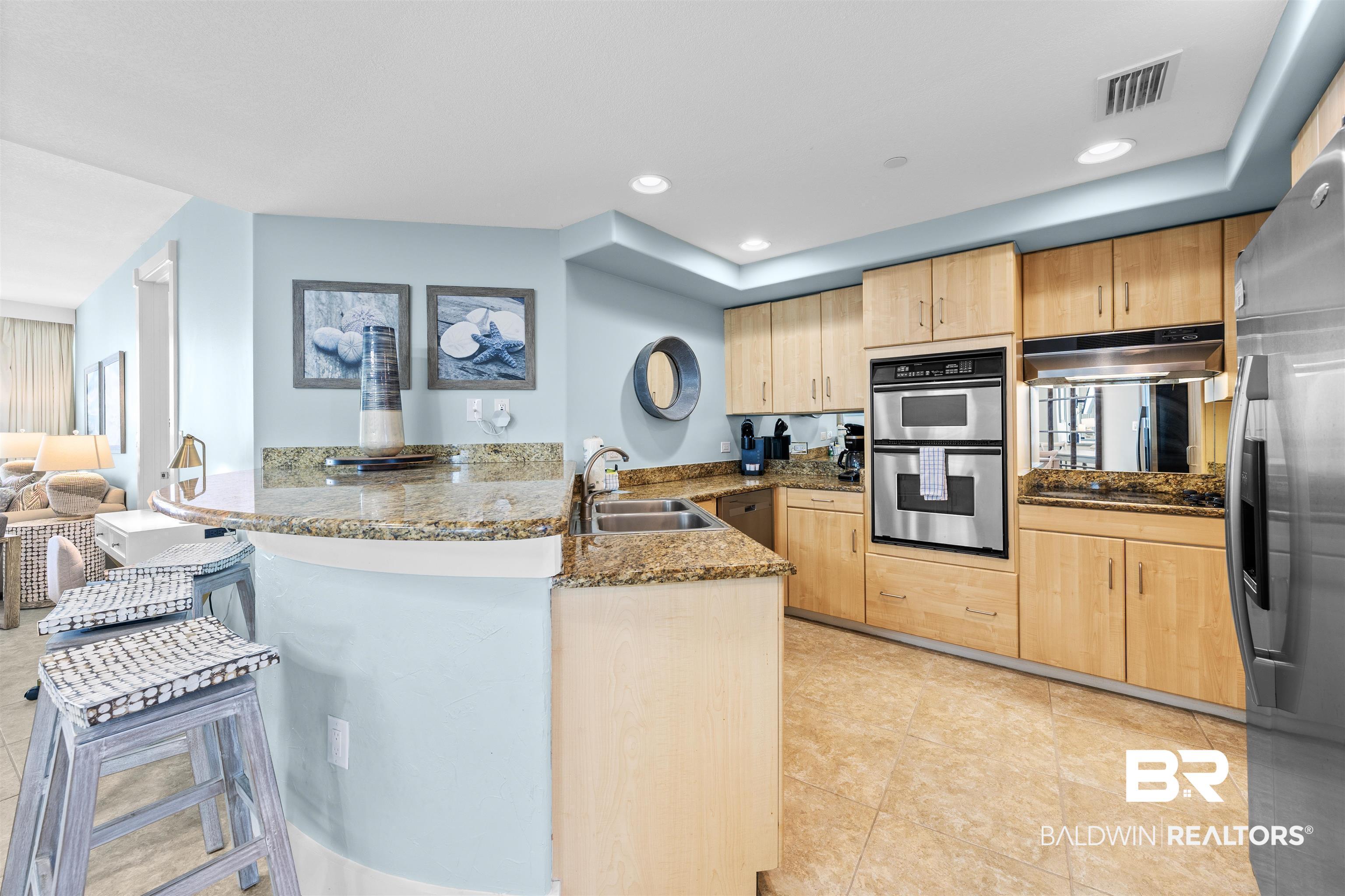 Image 4: Kitchen featuring dark stone countertops, a peninsula, stainless steel appliances, light wood finish cabinets, and recessed lighting