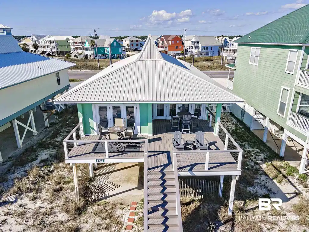 Image 1: Back of property with a deck, a metal roof, outdoor dining space, and a residential view