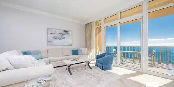 Image 2: Tiled living area featuring expansive windows, ornamental molding, ceiling fan, and a water view