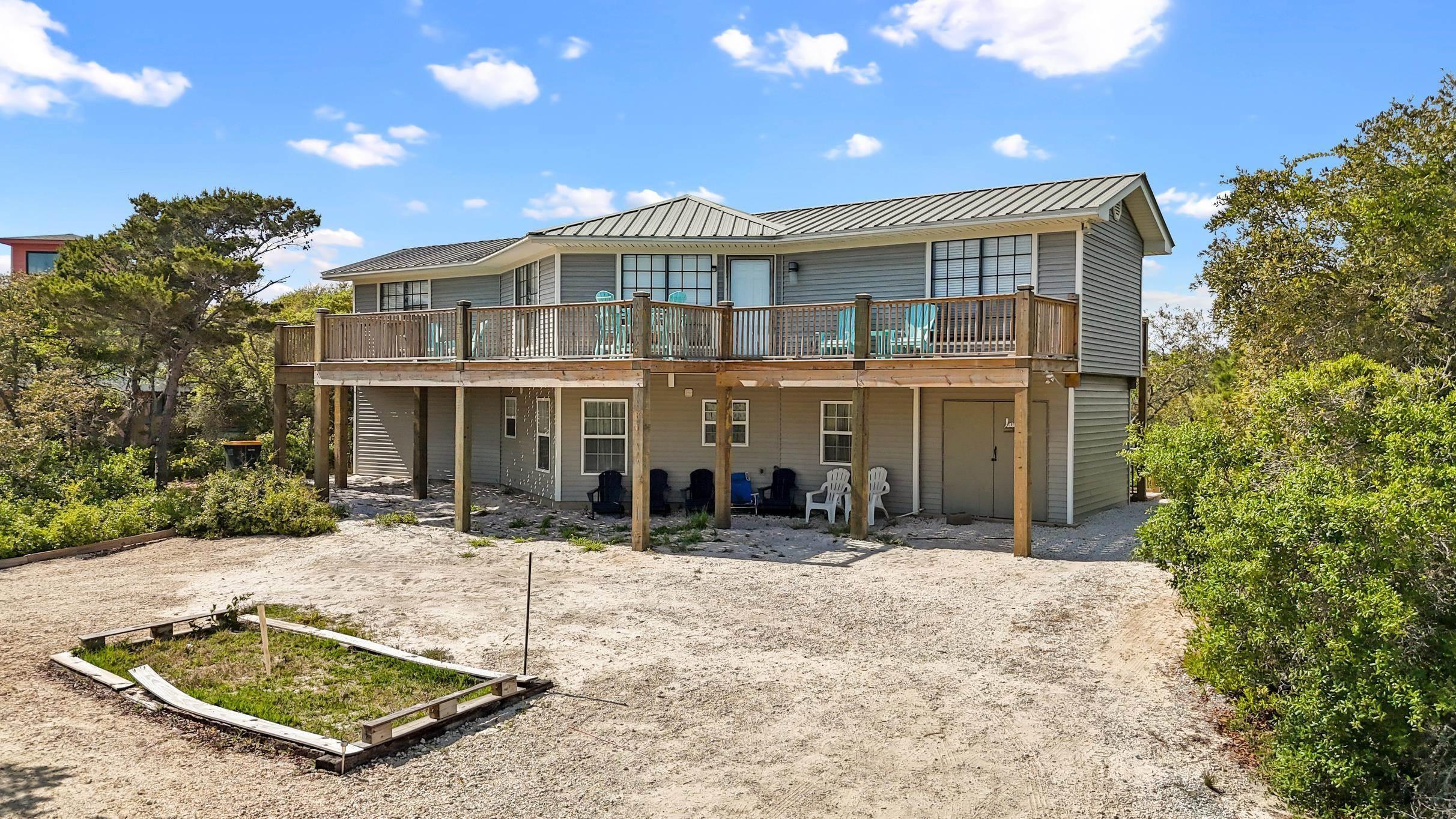 Image 3: Rear view of property featuring a wooden deck, a standing seam roof, and metal roof