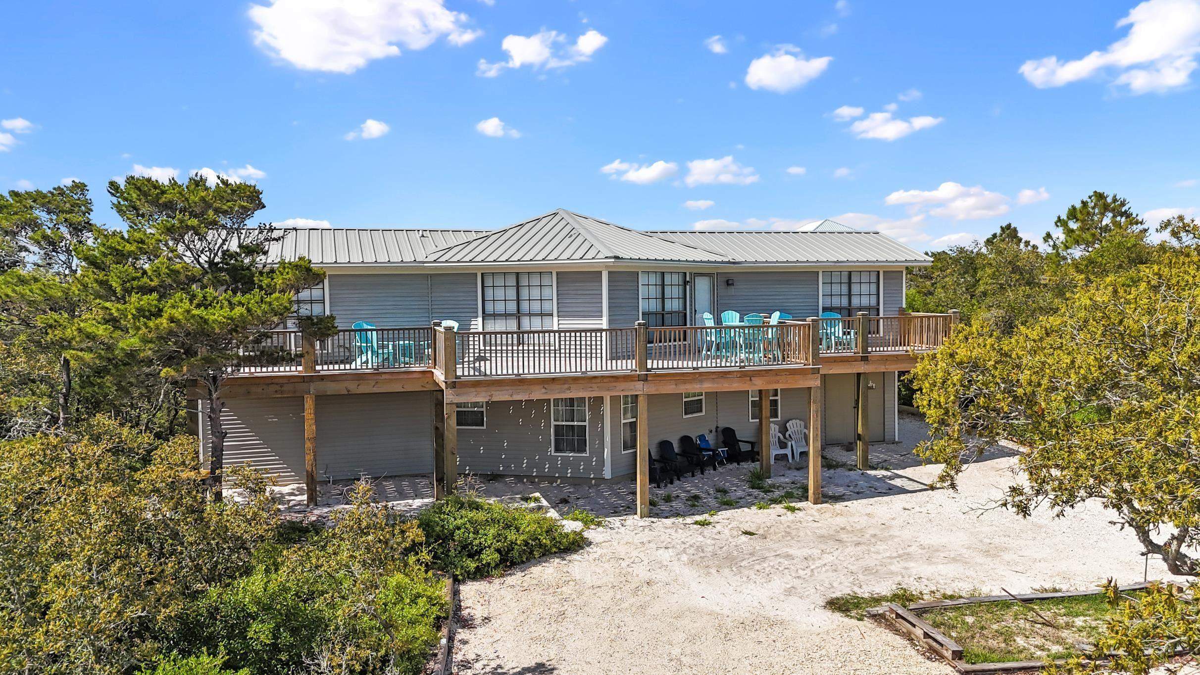 Image 4: Rear view of house featuring a wooden deck, metal roof, and a patio area