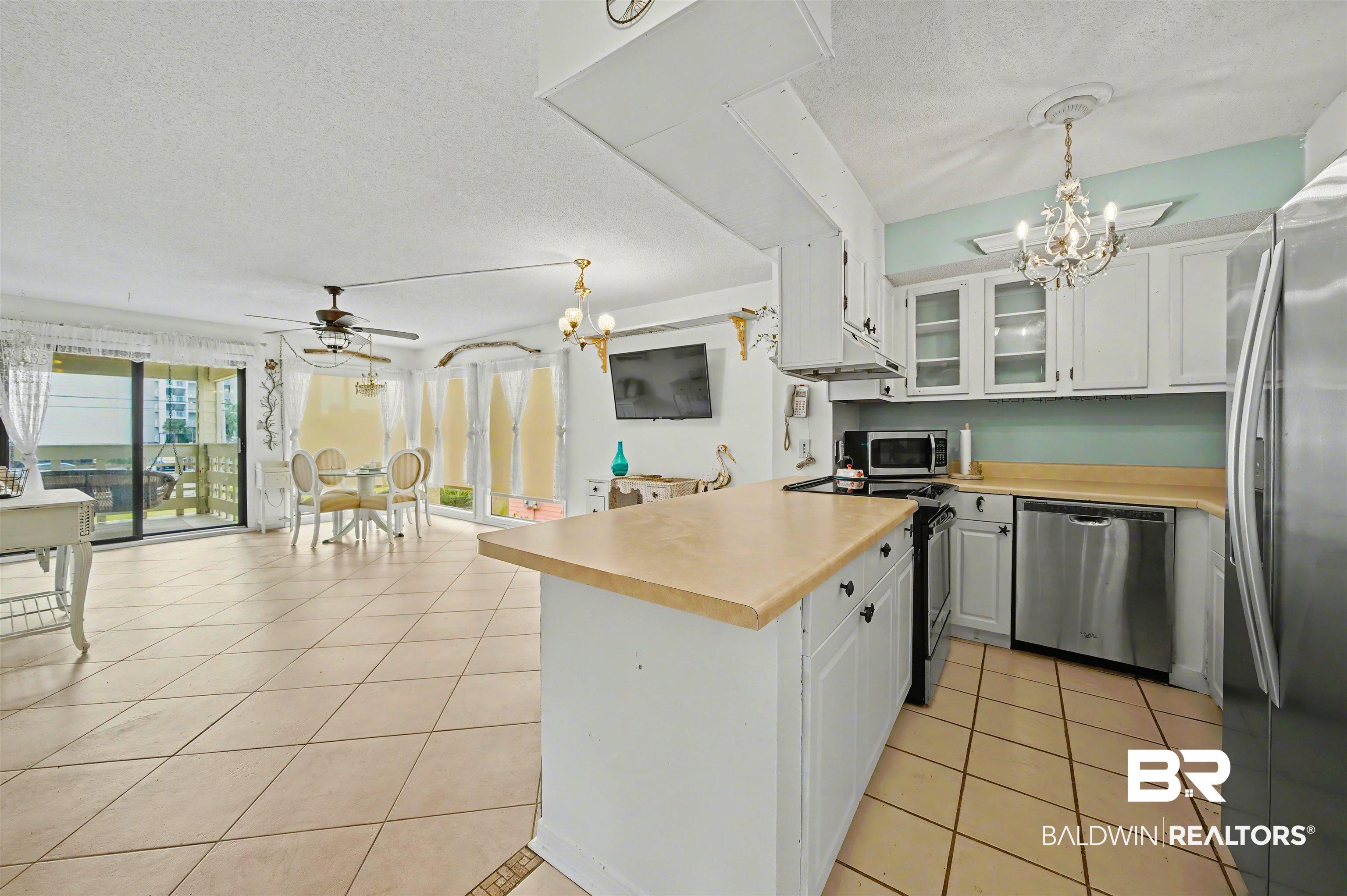 Image 4: Kitchen featuring a chandelier, white cabinets, a textured ceiling, and pendant lighting