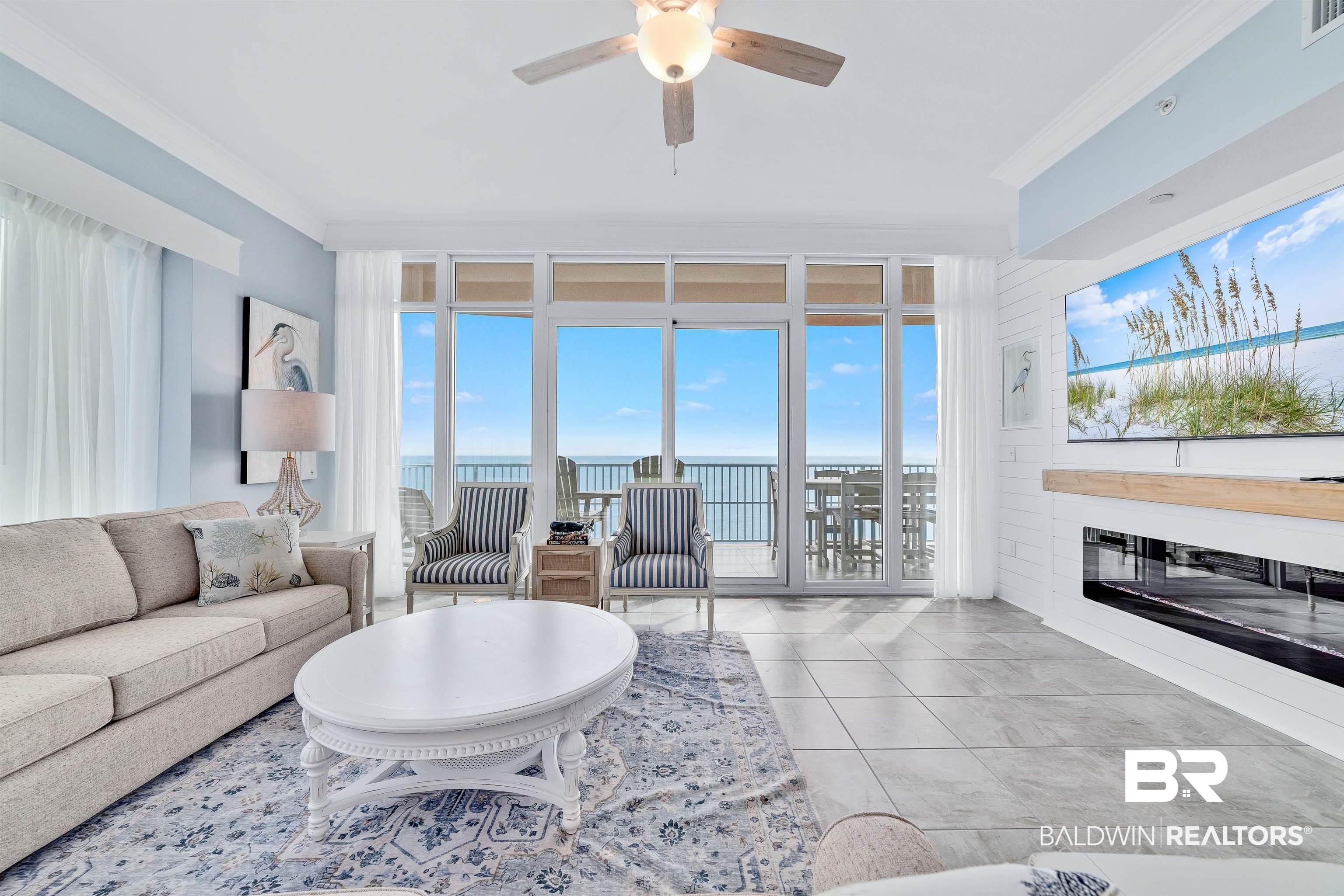 Image 3: Living area featuring a ceiling fan, crown molding, a glass covered fireplace, light tile patterned floors, and floor to ceiling windows