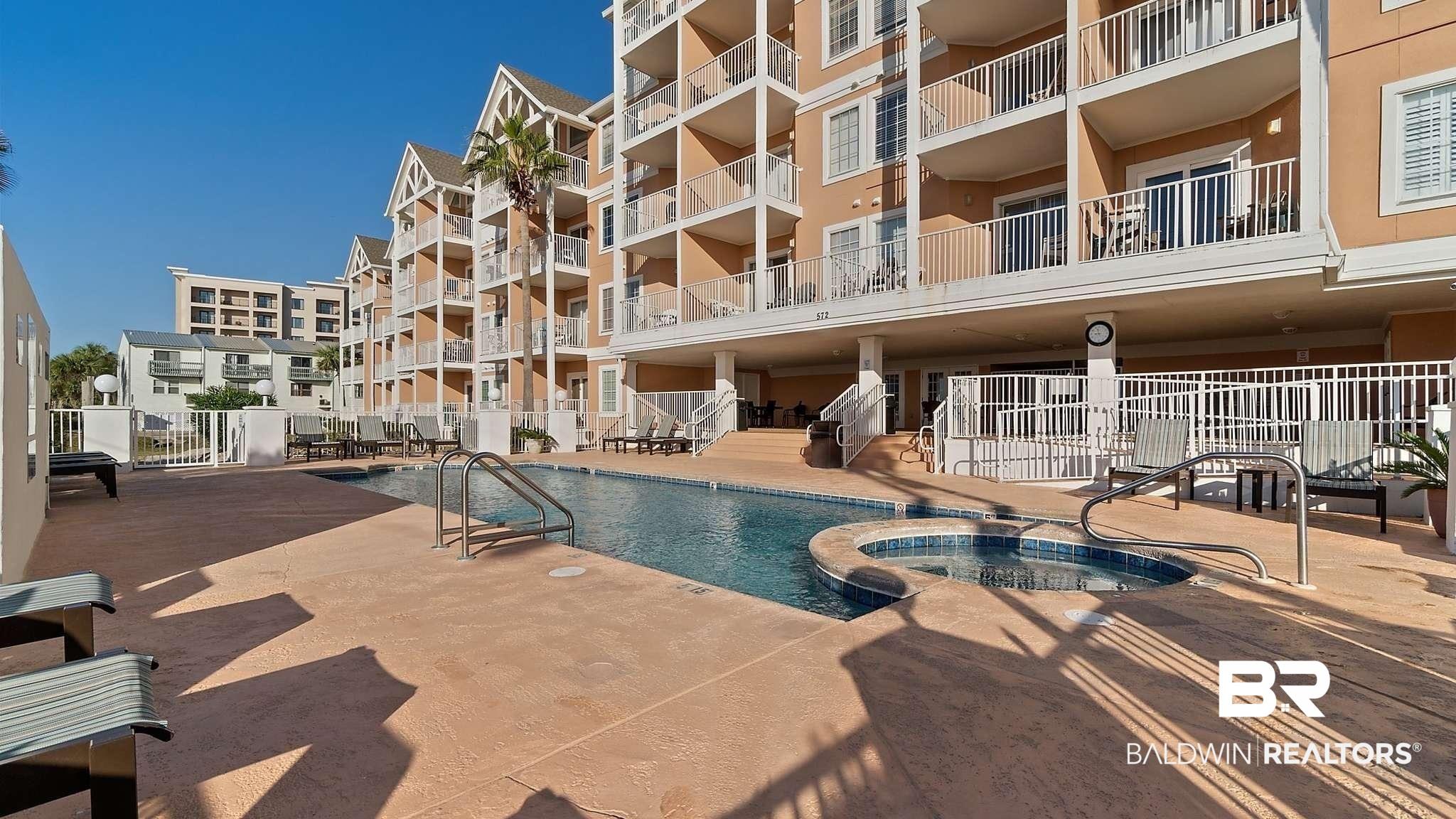 Image 3: Community pool featuring a hot tub and a patio