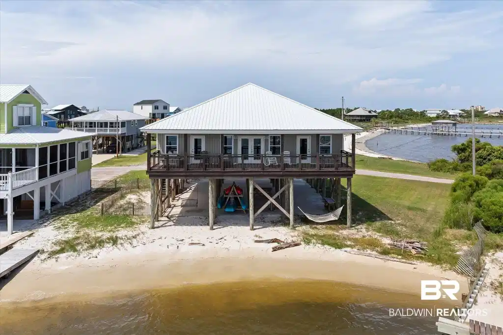 Image 1: Waterfront property featuring a raised structure, metal roof, and an elevated porch