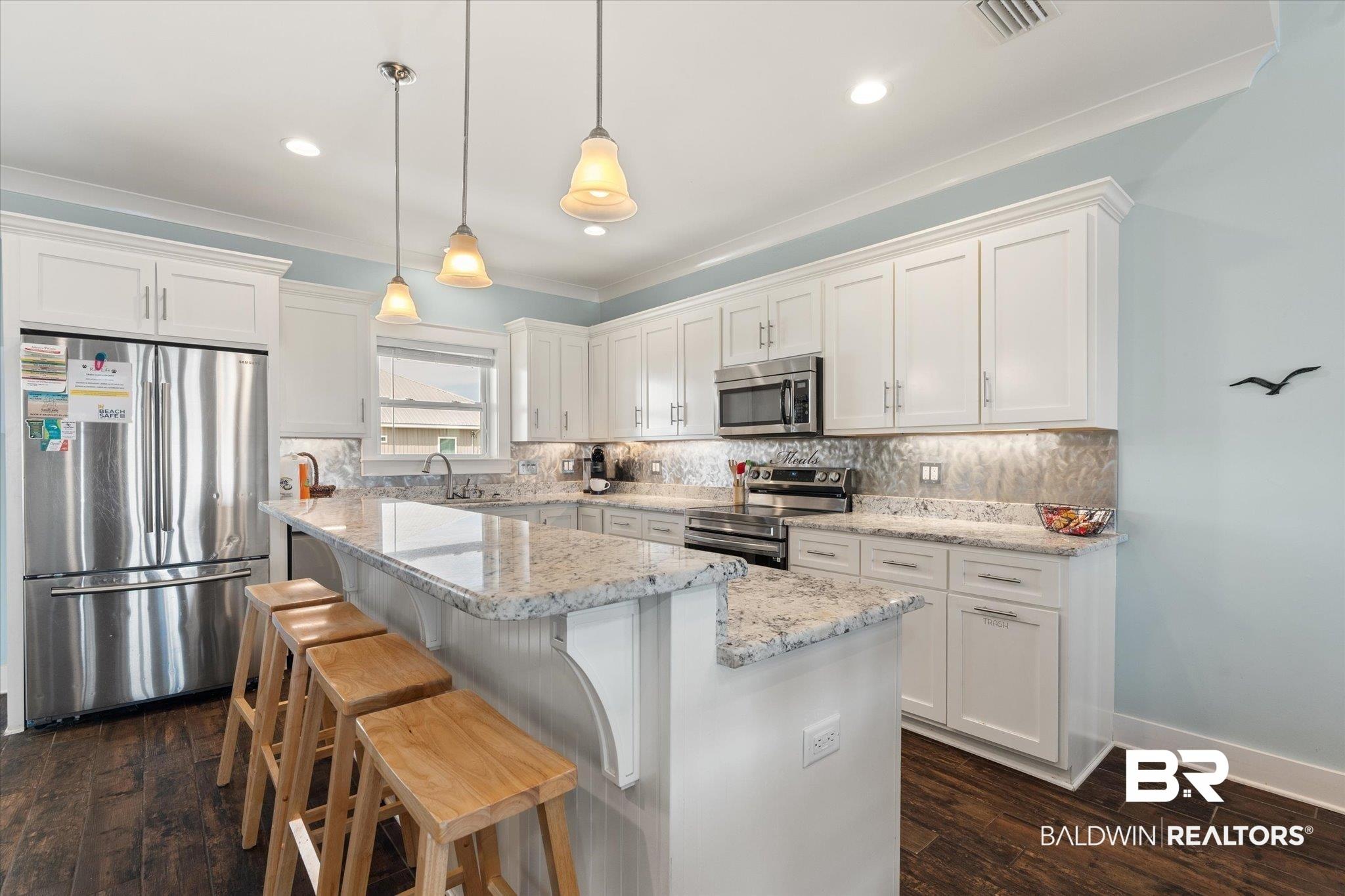 Image 3: Modern kitchen featuring white shaker cabinetry, stainless steel appliances, speckled stone countertops, and wood-finish flooring