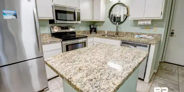 Image 3: Kitchen with stainless steel appliances, light stone counters, white cabinets, and a center island