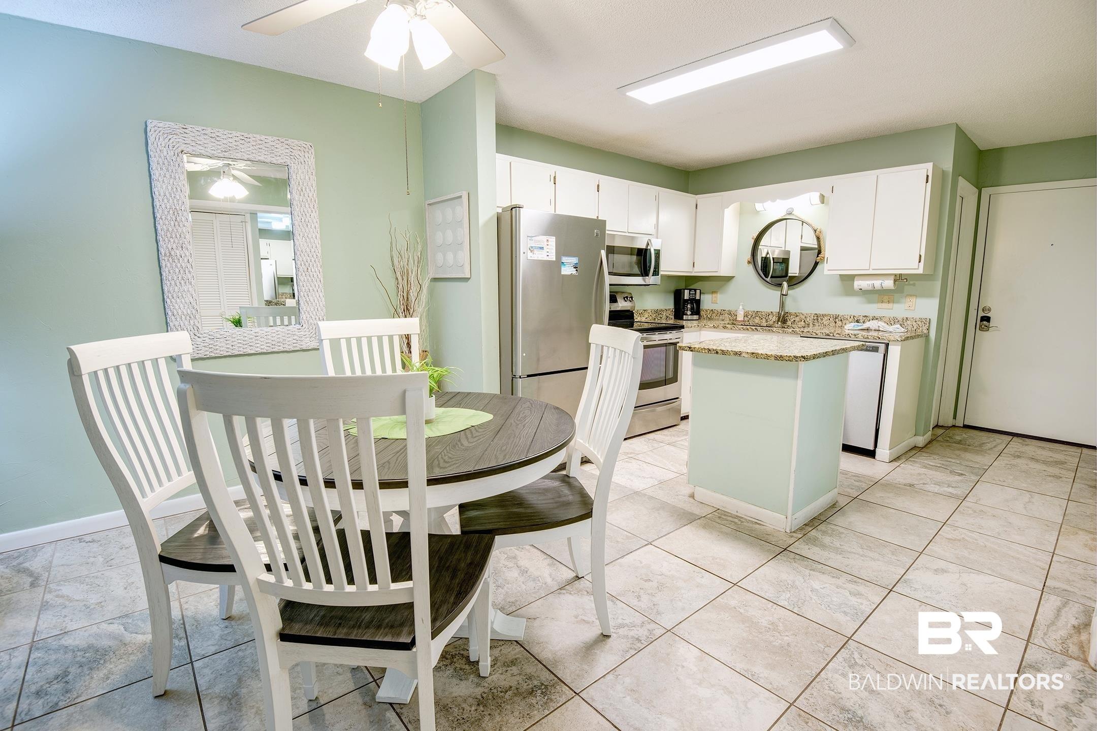 Image 4: Kitchen with white cabinetry, a kitchen island, stainless steel appliances, light stone countertops, and a ceiling fan
