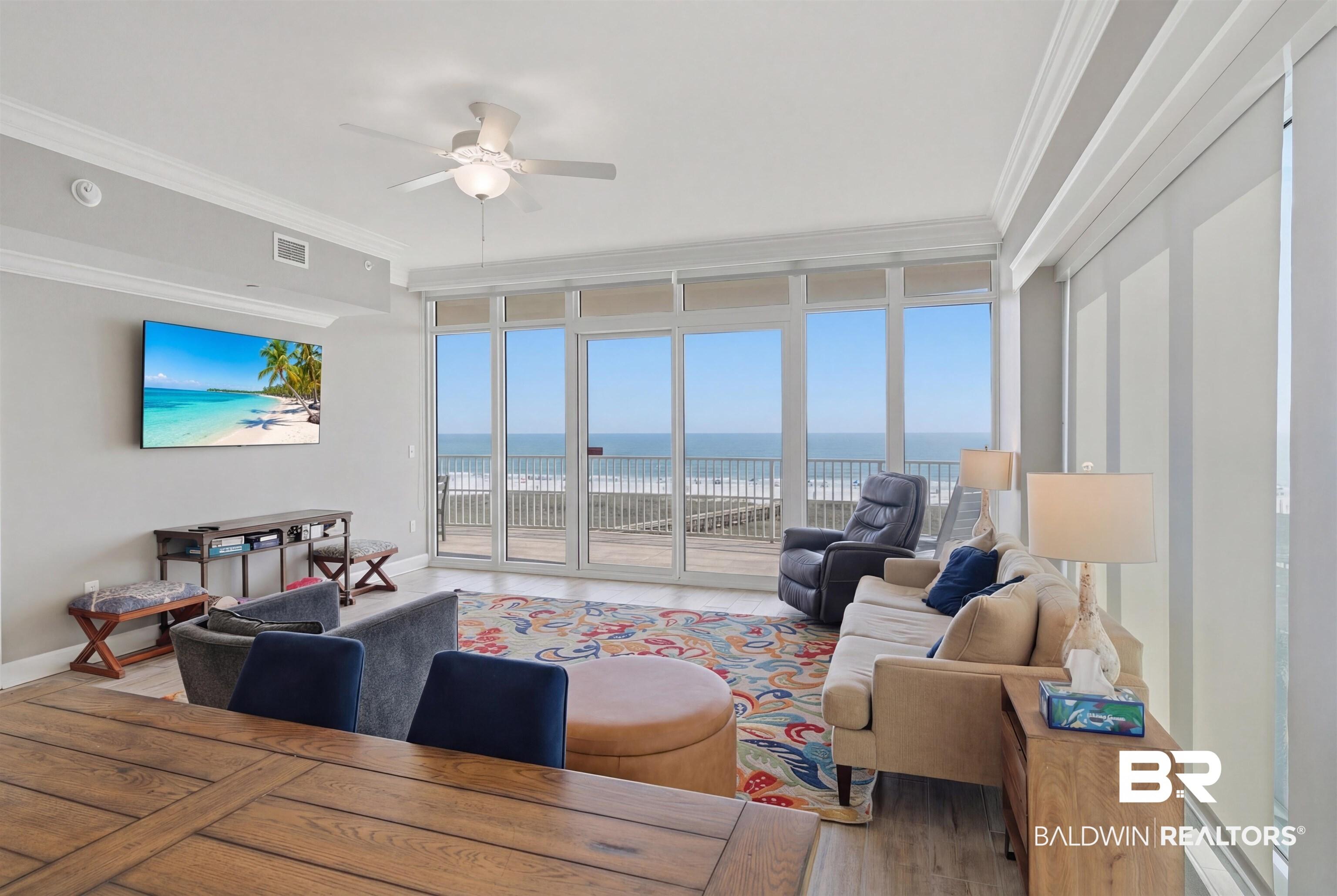 Image 3: Living room featuring expansive windows, crown molding, ceiling fan, and wood finished floors