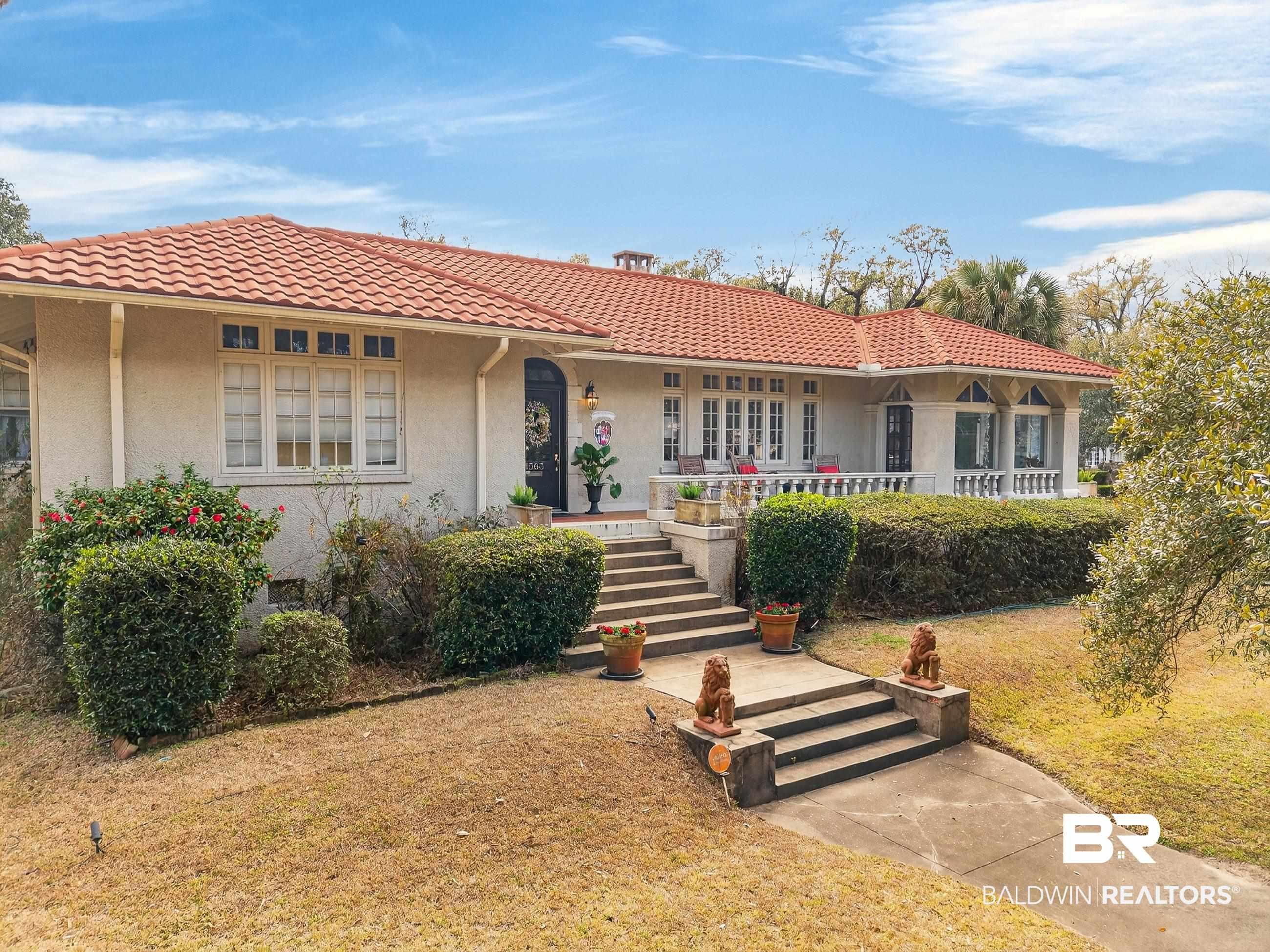 Image 1: Mediterranean / spanish-style home featuring covered porch, stucco siding, a front yard, and a tile roof
