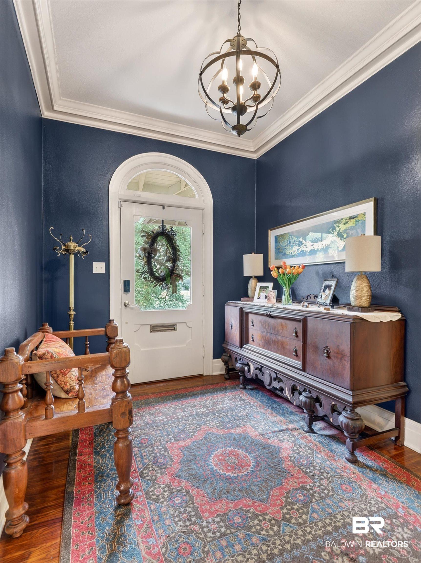 Image 4: Entryway with hardwood / wood-style flooring, ornamental molding, and hanging lights