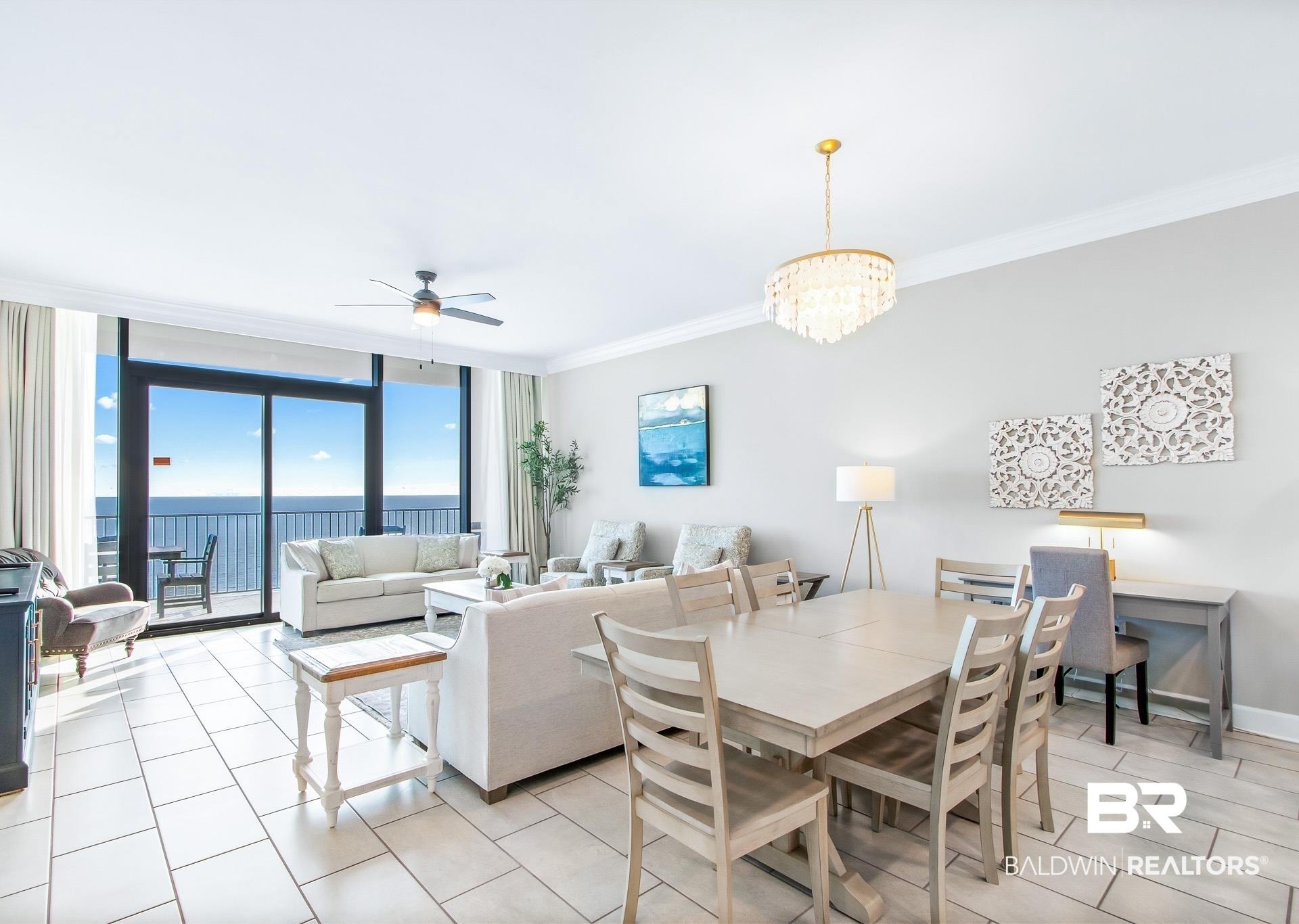 Image 3: Open-concept living area featuring large format tile flooring, crown molding, and a full wall of sliding glass doors opening to a balcony with ocean views