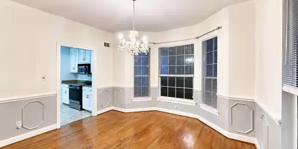 Image 2: Hardwood flooring throughout featuring a bay window, crown molding, and wainscoting
