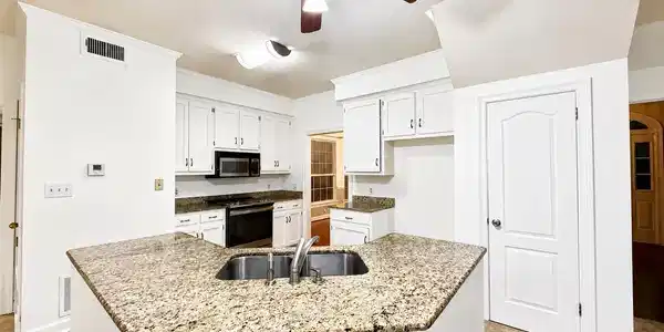 Image 3: Kitchen featuring a peninsula with integrated sink, granite-style countertops, white cabinetry, and stainless steel appliances