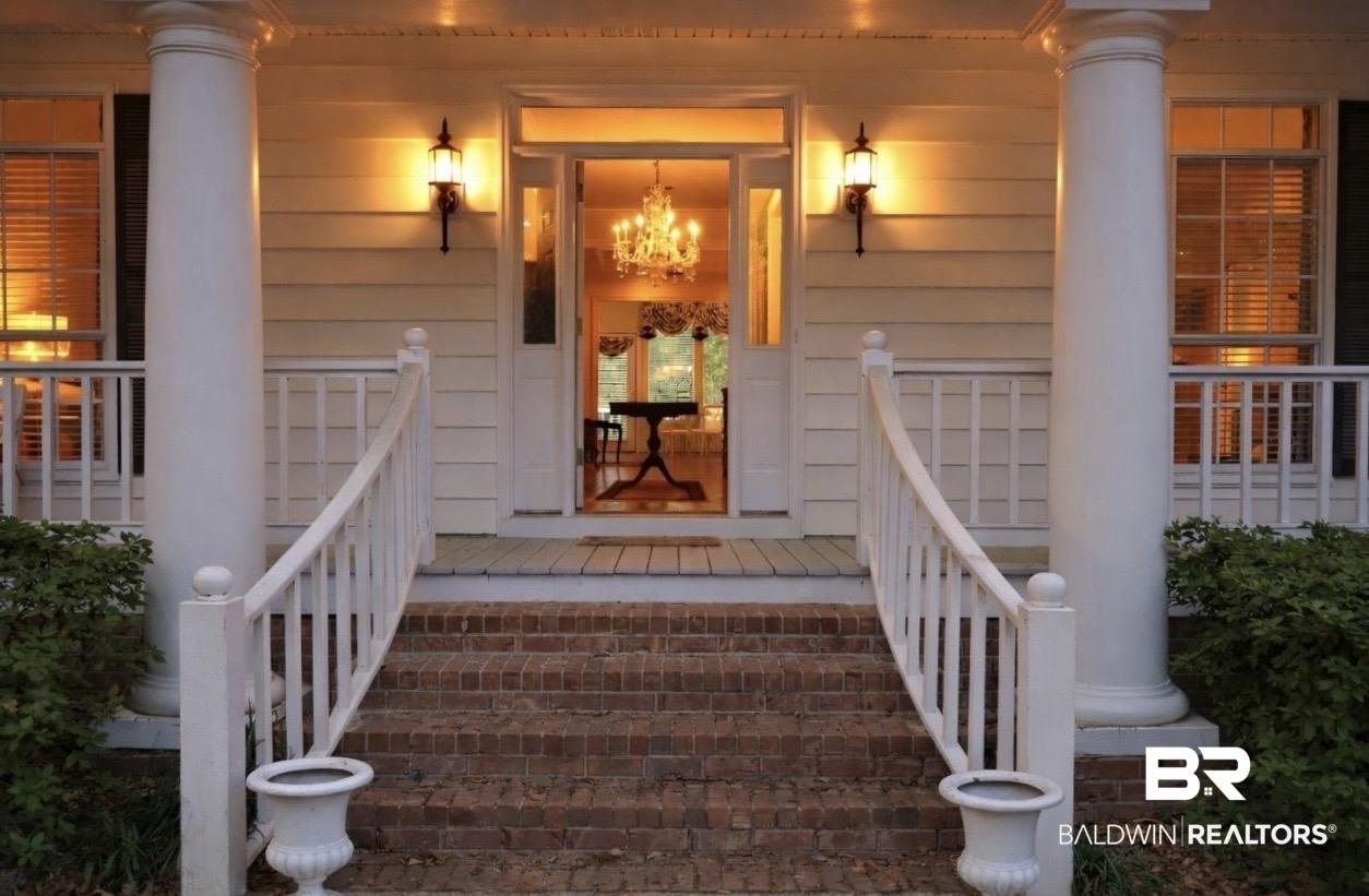 Image 4: Classic architectural facade featuring brick stairs, white columned porch, white railings, and matching wall sconces