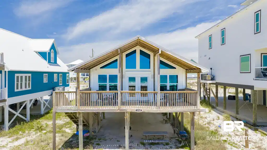 Image 1: Elevated coastal residence featuring a prominent A-frame architectural style with expansive windows