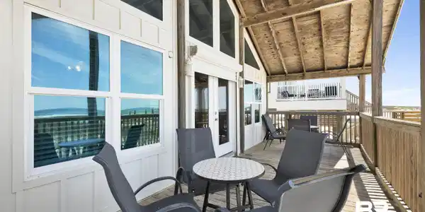 Image 3: Expansive covered deck featuring natural wood flooring and railing