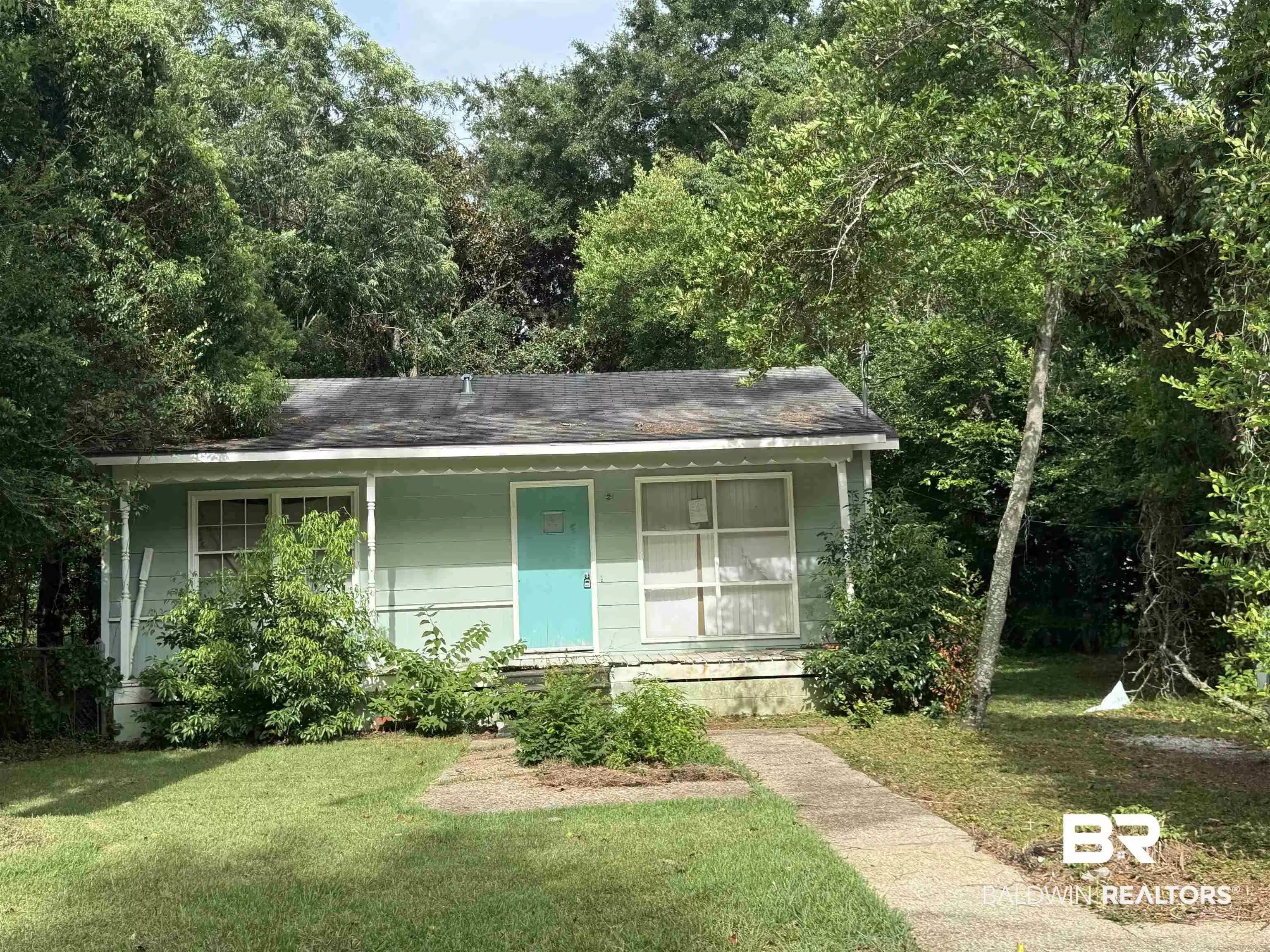 Image 1: Mint green exterior with a contrasting turquoise front door, featuring a covered front porch and a concrete walkway