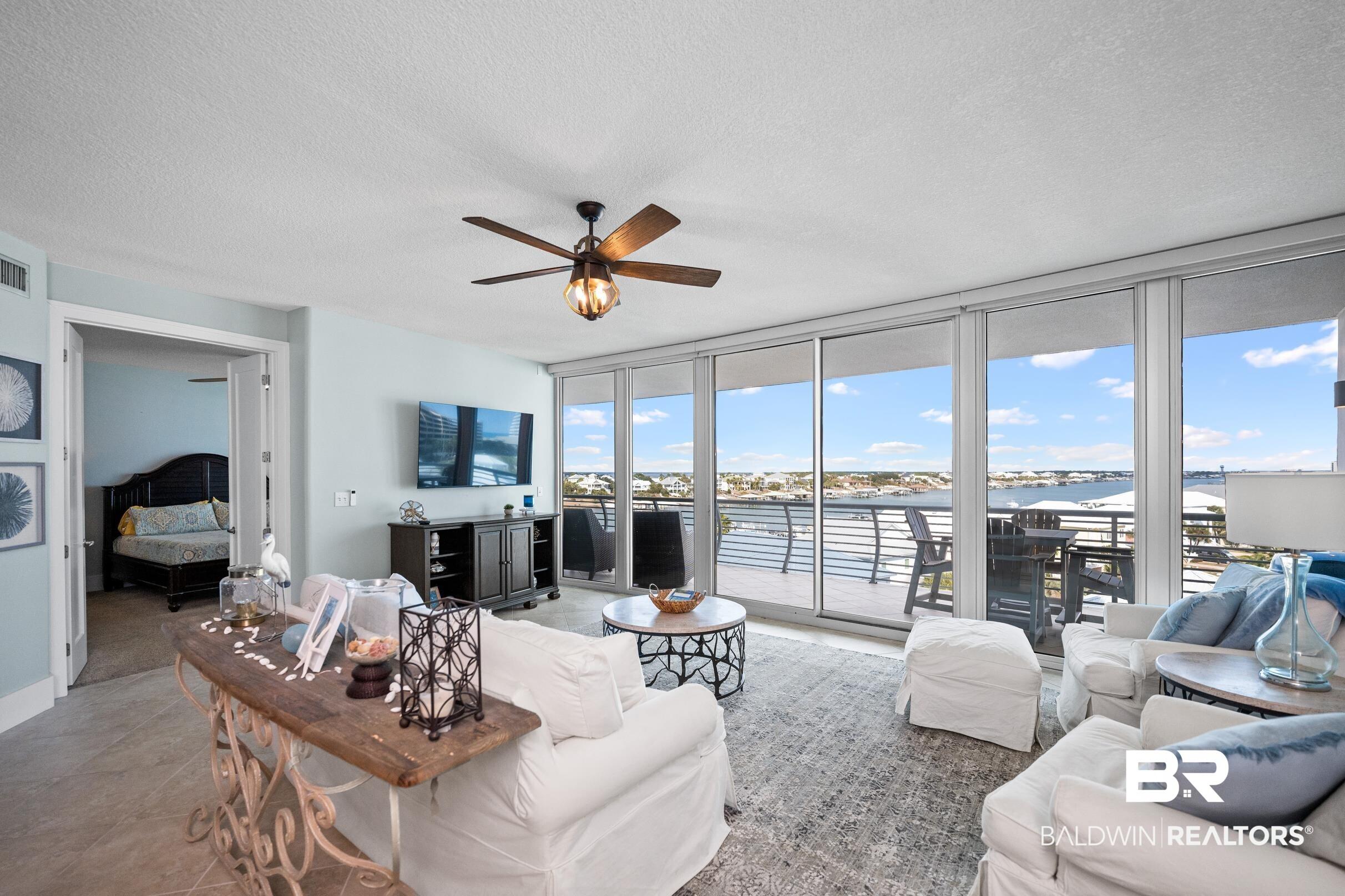 Image 3: Living area featuring expansive windows, a textured ceiling, and ceiling fan