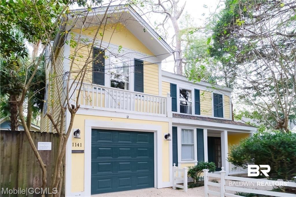 Image 2: View of front of house with stucco siding, a garage, fence, and a balcony
