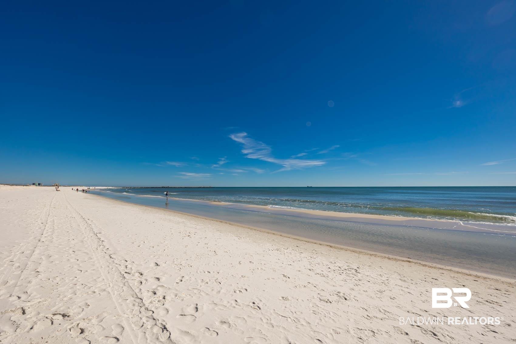 Image 4: Expansive sandy beach with clear blue water and bright blue skies